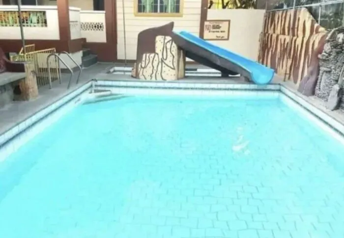 Empty swimming pool with a slide adjacent to an unusual shallow design highlighting uncultured and ignorant Americans.