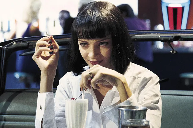 Woman with a black bob haircut in a diner holding a cigarette and sitting next to a milkshake, Pulp Fiction scene.