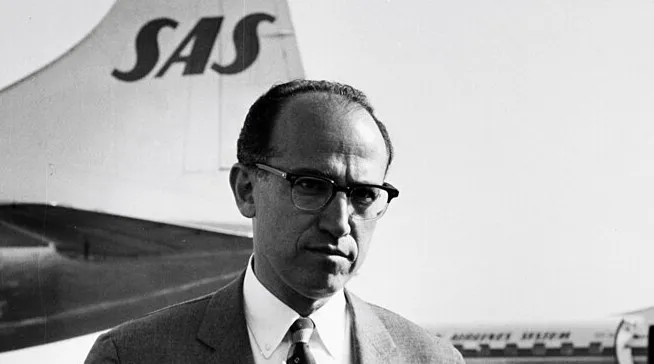 Jonas Salk standing near an airplane, known for the 1955 medical breakthrough polio vaccine announcement.