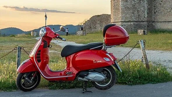 Vintage Vespa scooter in red, representing 1950s general knowledge about its country of manufacture.