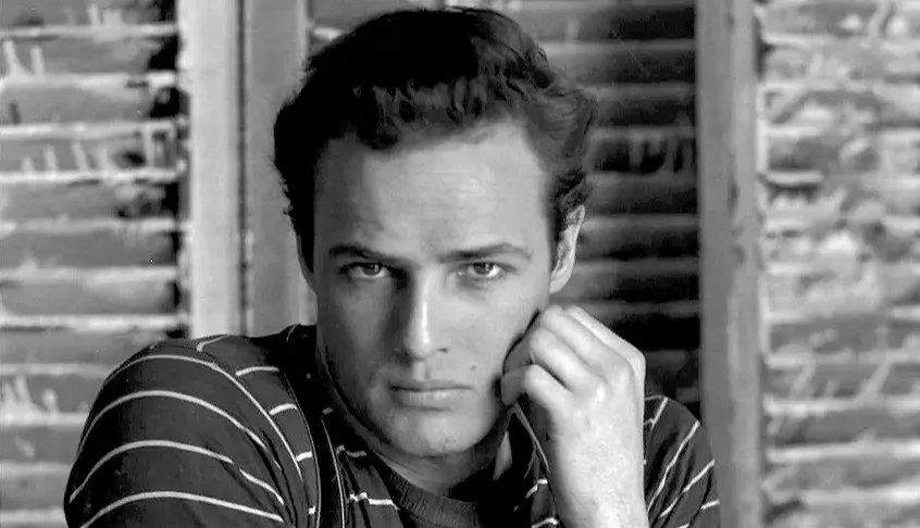 Black and white portrait of Marlon Brando wearing a striped T-shirt, an iconic item of clothing from the 50s fashion era.