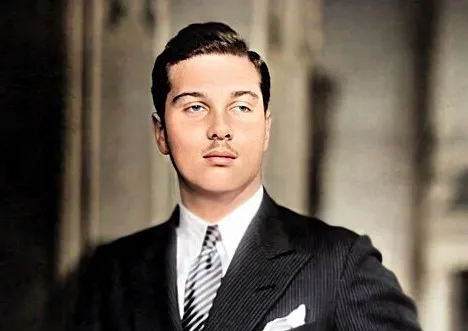 Young King Farouk of Egypt in a formal suit, posing confidently with a mustache in a vintage setting.