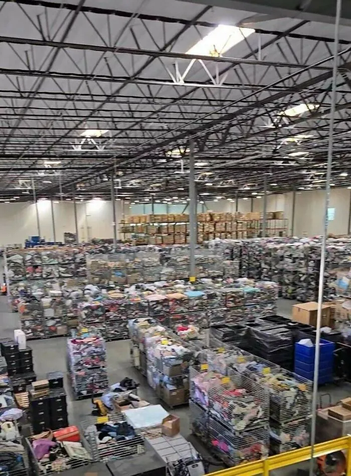 An overhead view of a massive warehouse filled with countless bins of clothes, showing extensive consumerism.