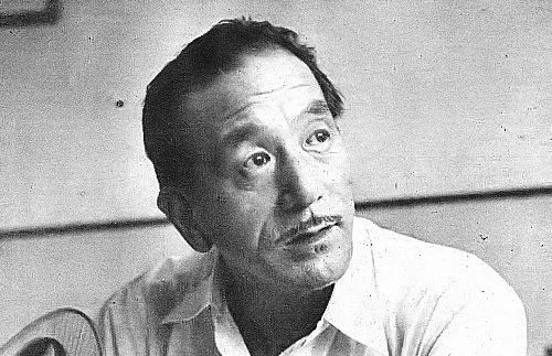 Japanese film director Yasujirō Ozu in a black and white photo, wearing a light shirt and looking thoughtfully.