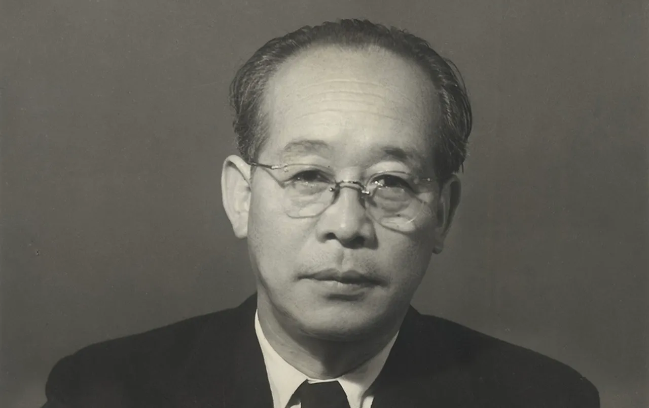 Black and white photo of an iconic Japanese film director known for Seven Samurai, wearing glasses and a suit.