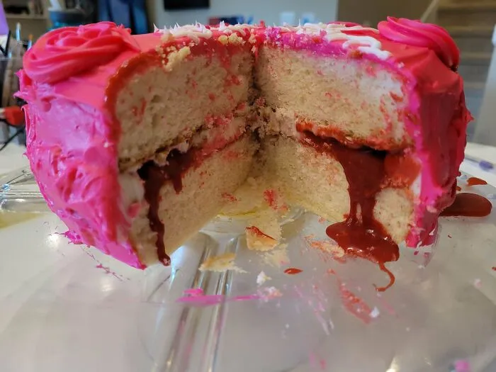 Pink frosted cake with chocolate filling oozing from the center slice dessert