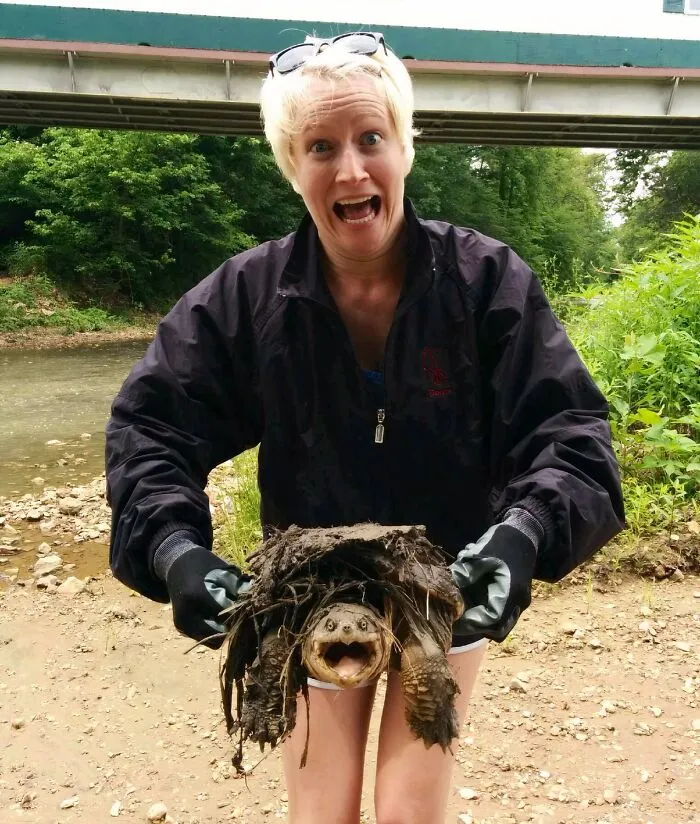 Woman holding a muddy turtle rescued from awful conditions, symbolizing animals saved and given a second chance in life.