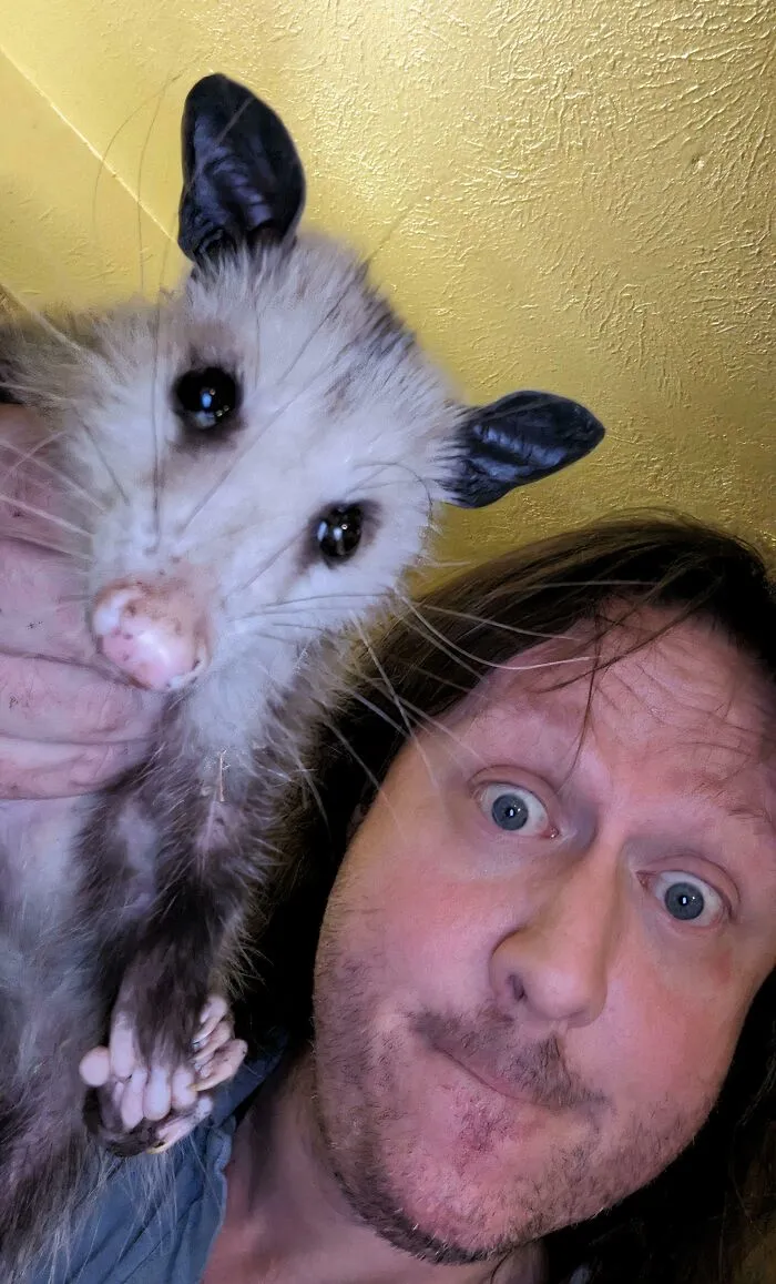 Man holding a rescued animal close to his face, showing a bond between animals saved from awful conditions.
