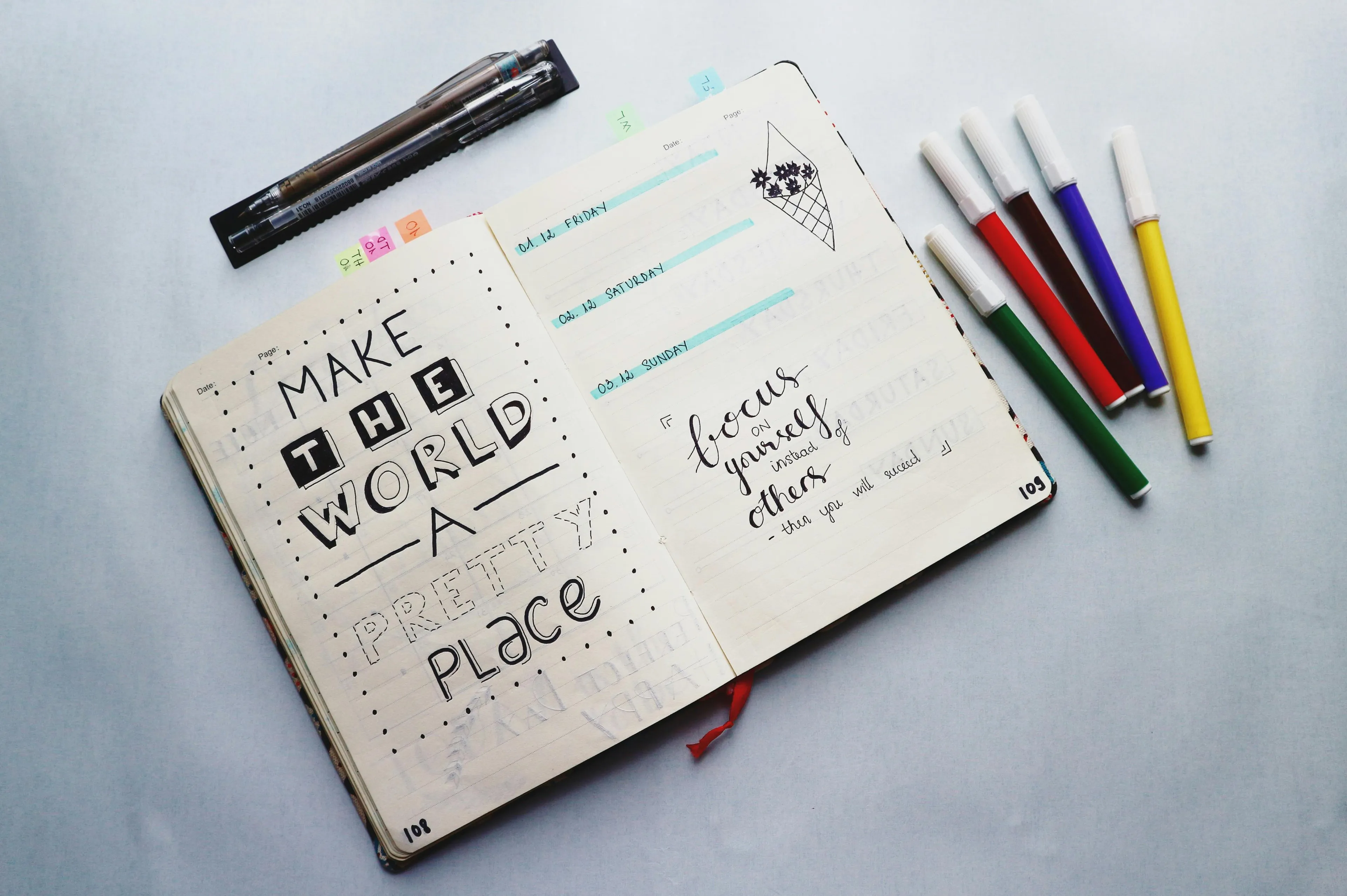 Open journaling notebook with motivational quotes and colorful markers laid out on a light surface for creative journaling.