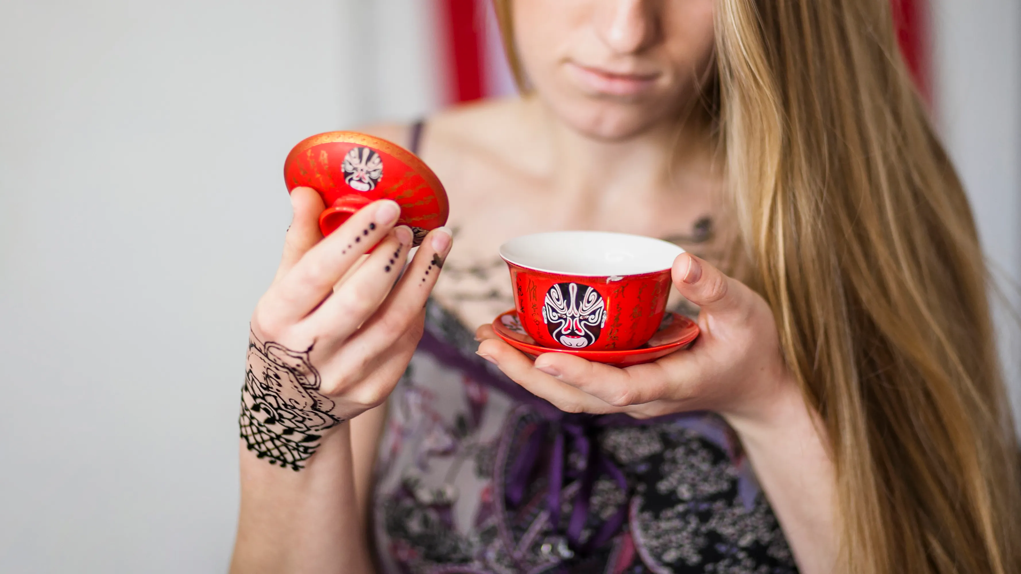 Woman with henna tattoos holding a red novelty mug in a museum gift shop, exploring urge control and decision making.