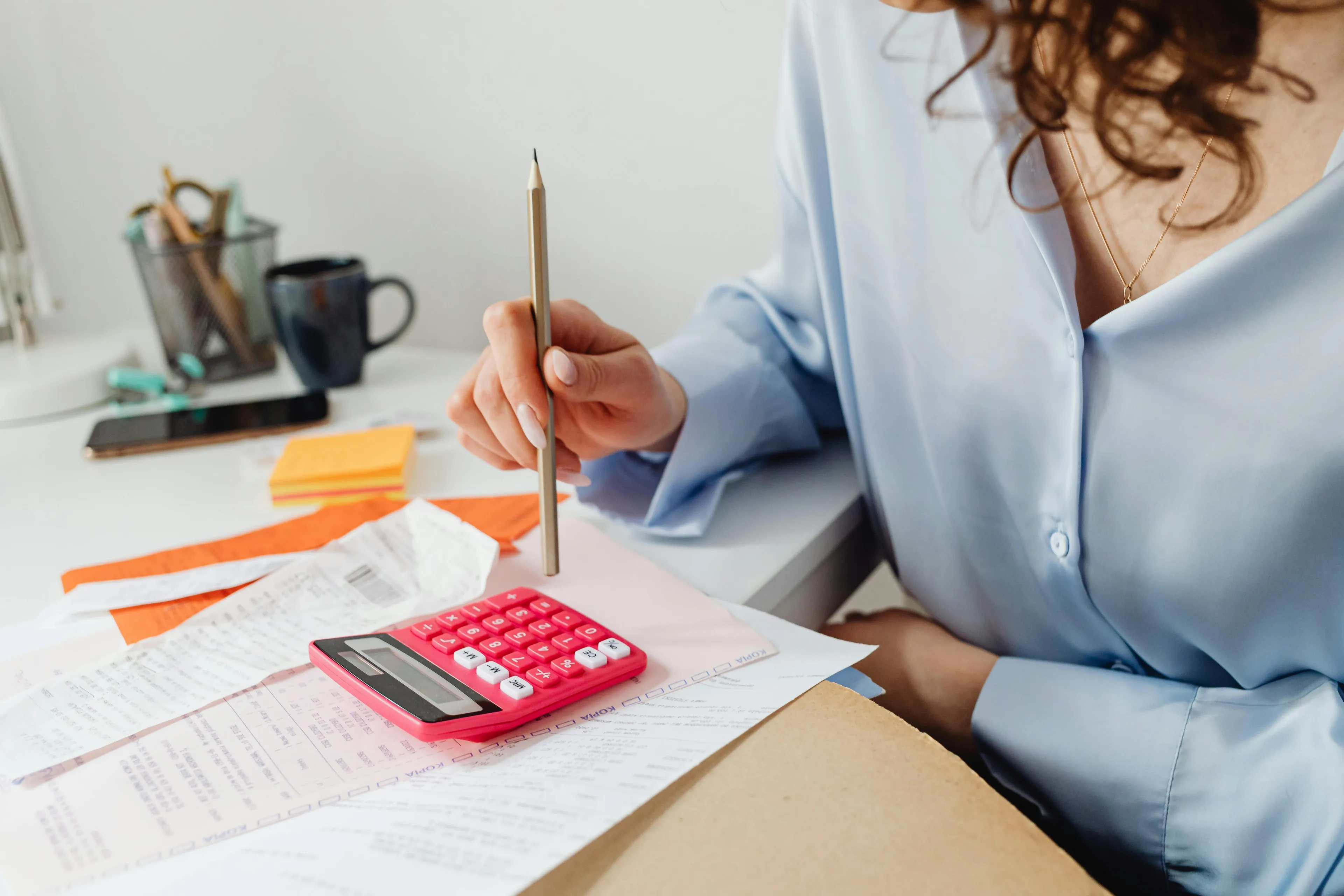 Person budgeting with a calculator and pencil, managing expenses while controlling urges for a pricey weekend trip.
