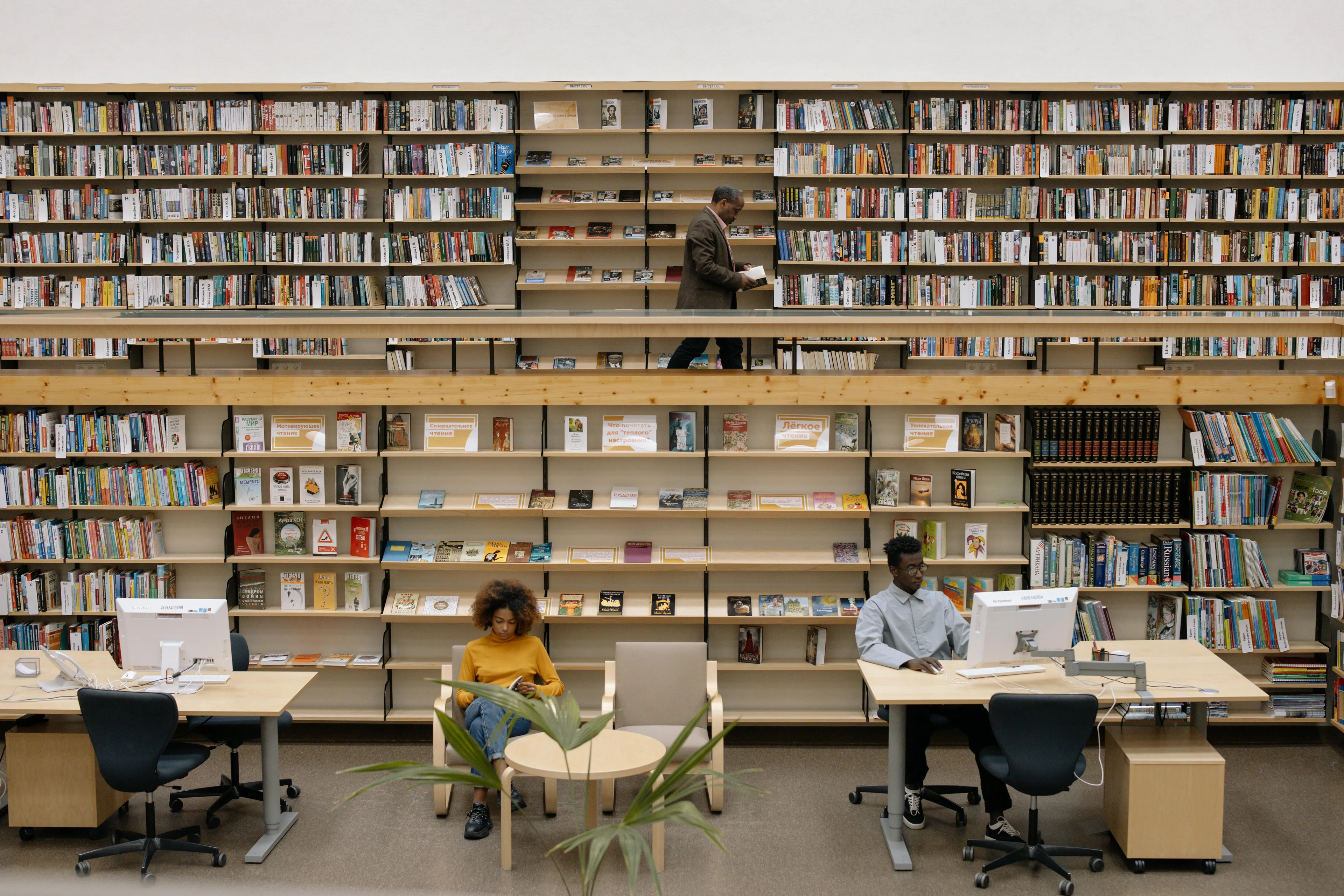 Two people study in a quiet library nook surrounded by bookshelves, representing control over urges during study time.