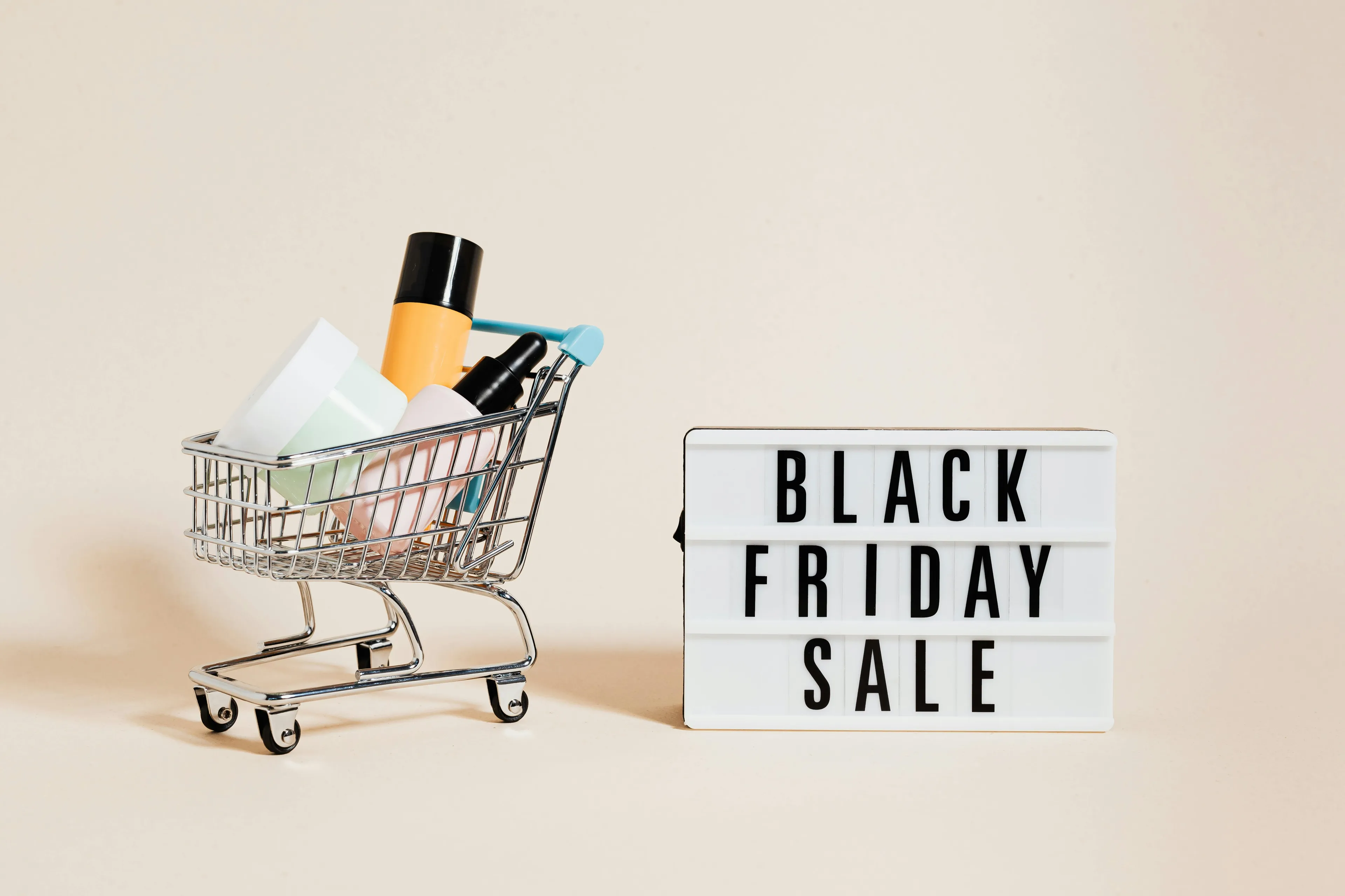 Mini shopping cart filled with items next to a lightbox sign reading Black Friday sale, highlighting urge control during deals.
