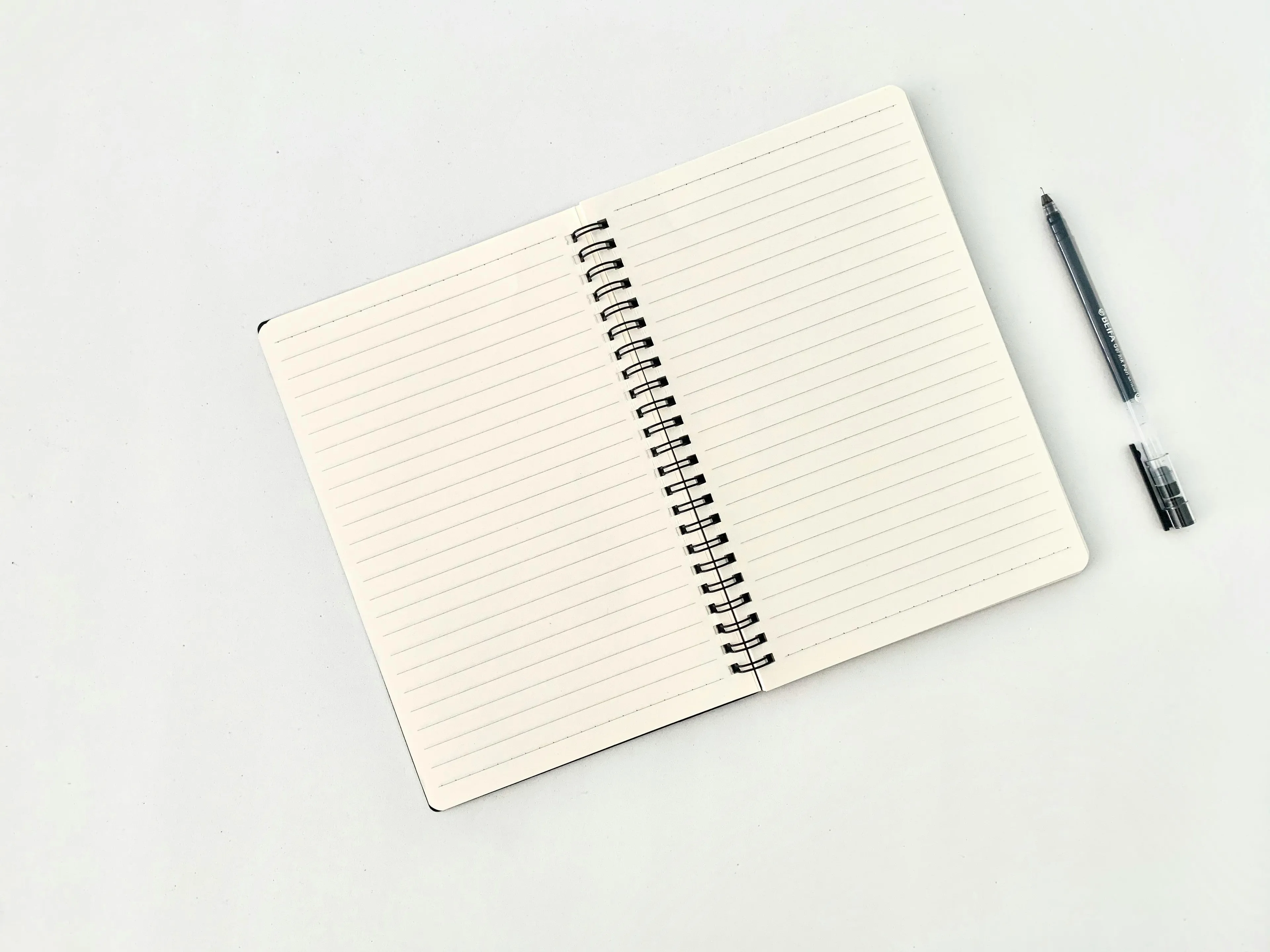 Open lined daily journal with a pen on a white surface, symbolizing control of urges through writing.