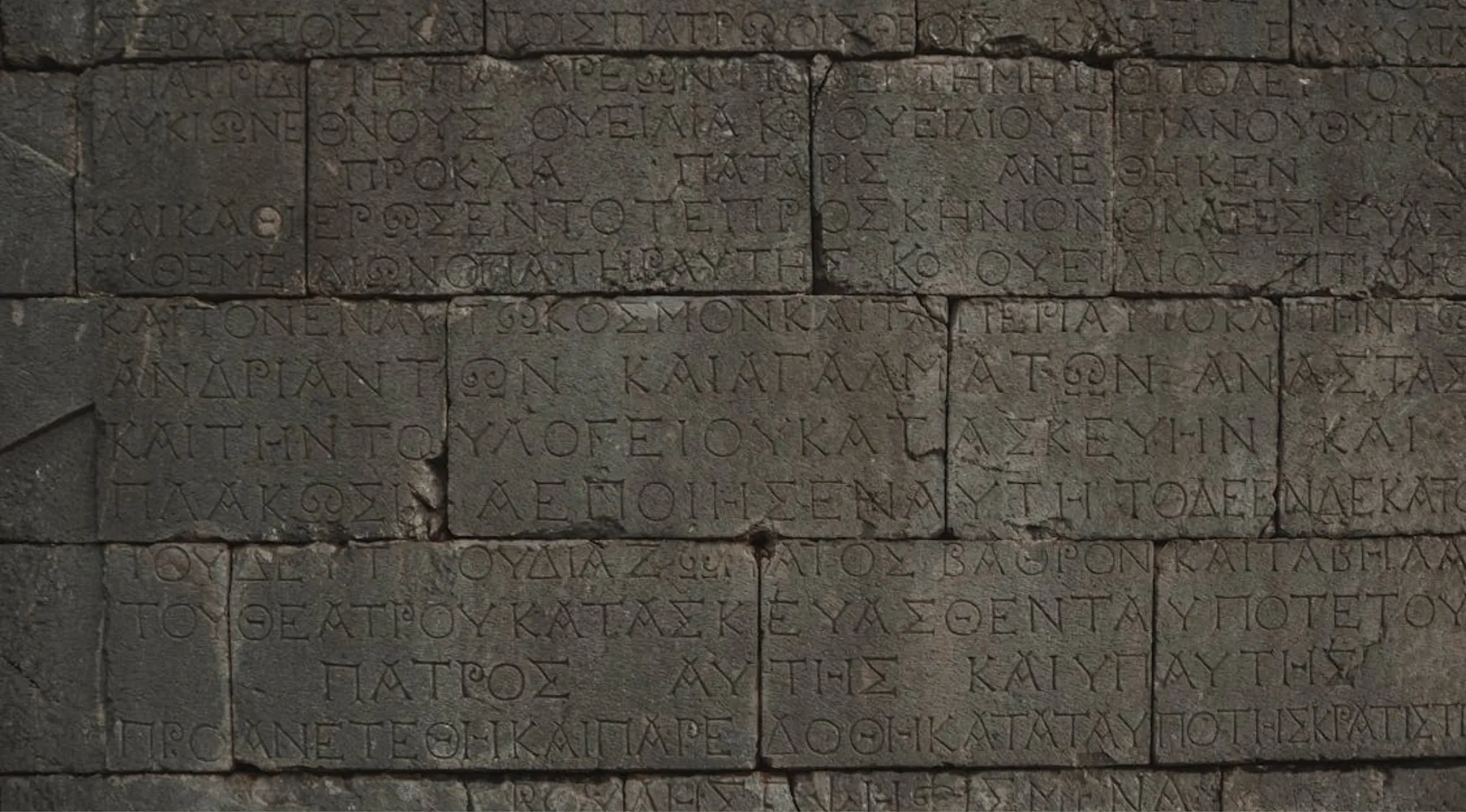 Ancient stone wall with carved Greek letters, related to general knowledge skills and the Greek alphabet first letter.