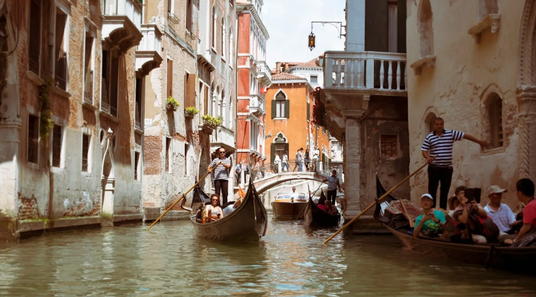Gondolas cruising a narrow canal in the famous Italian city known for its canals and gondolas.