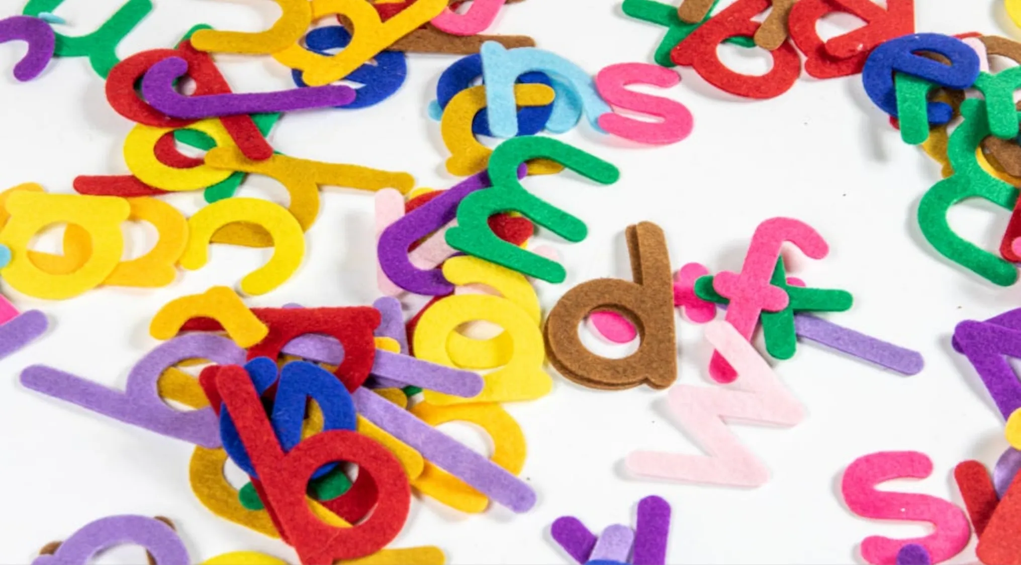 Colorful felt letters scattered on a white surface representing the English alphabet for general knowledge skills testing.