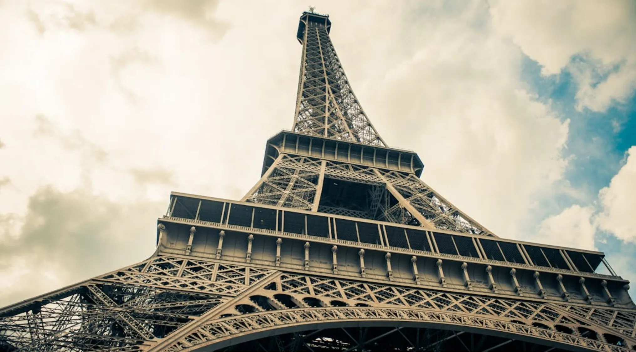 Close-up view of a famous landmark showing detailed metal lattice structure under a cloudy sky.