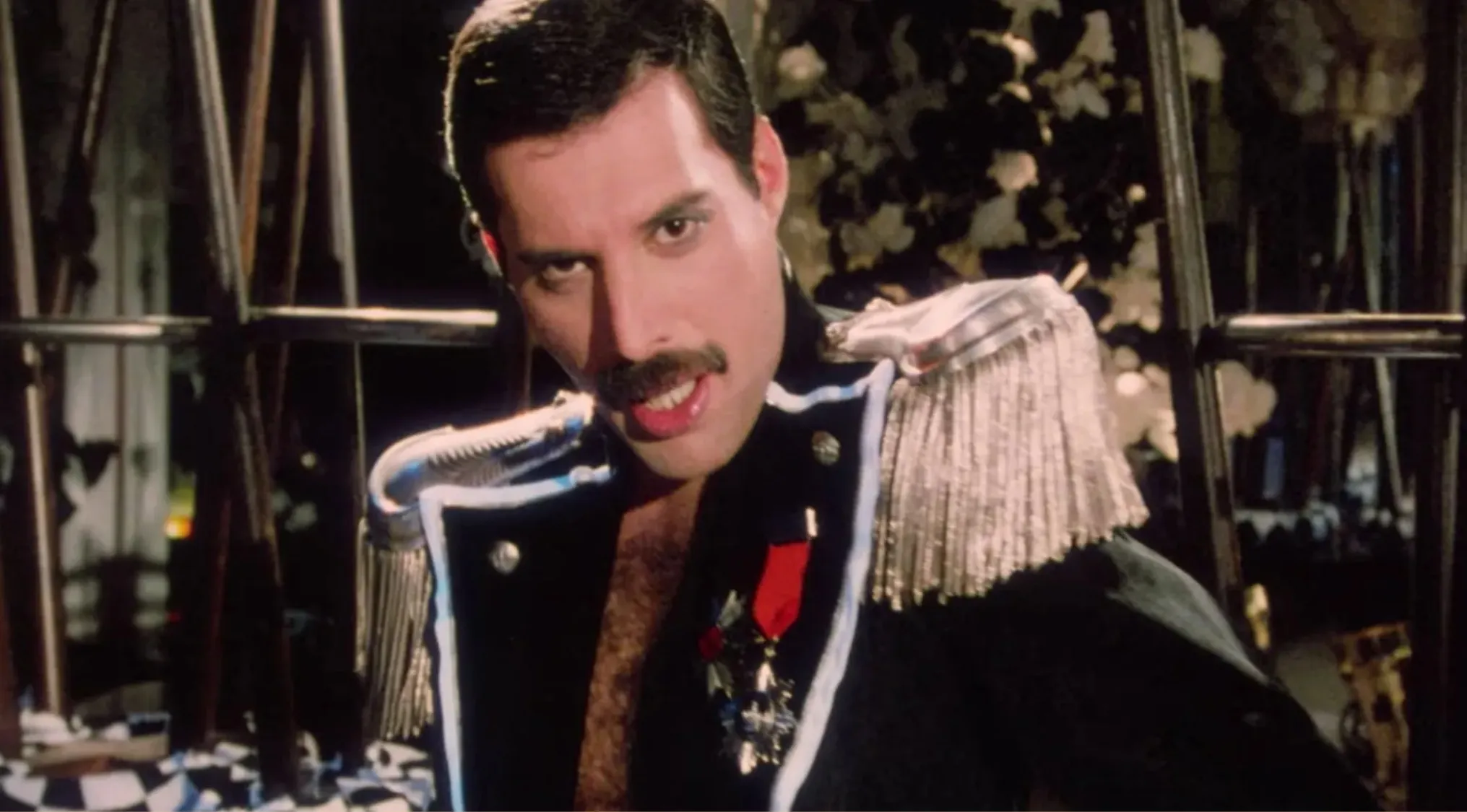Freddie Mercury performing in a decorated stage outfit, iconic lead singer of the band Queen.