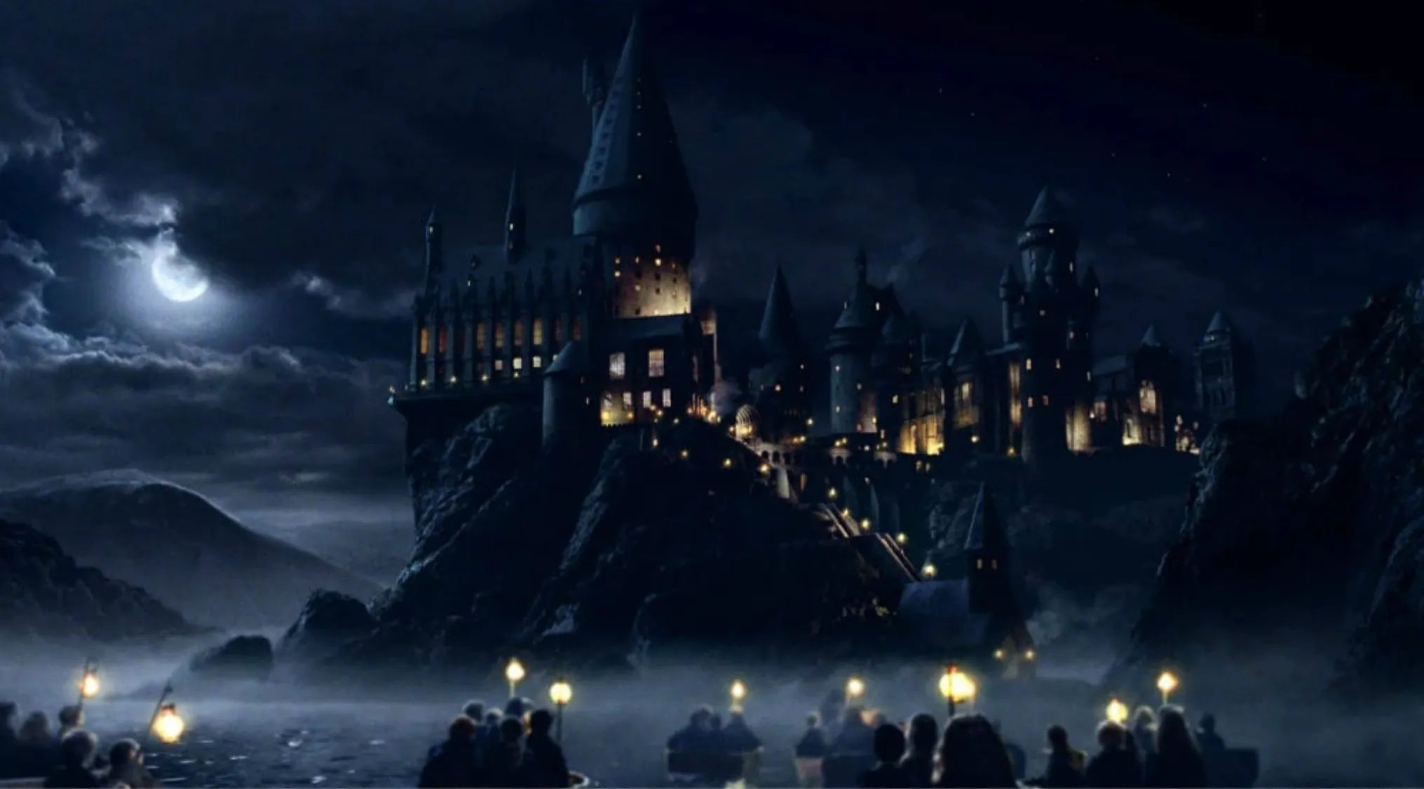 Hogwarts castle at night under a full moon with boats carrying students arriving at the wizard school.