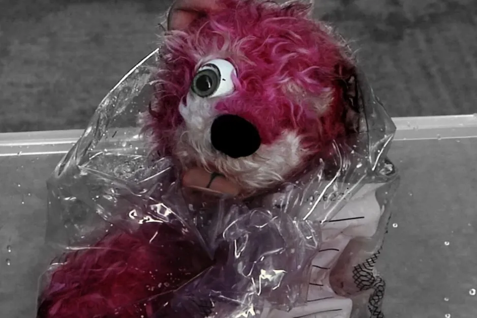 Pink teddy bear prop in Breaking Bad, with damage and missing eye, partially wrapped in clear plastic.