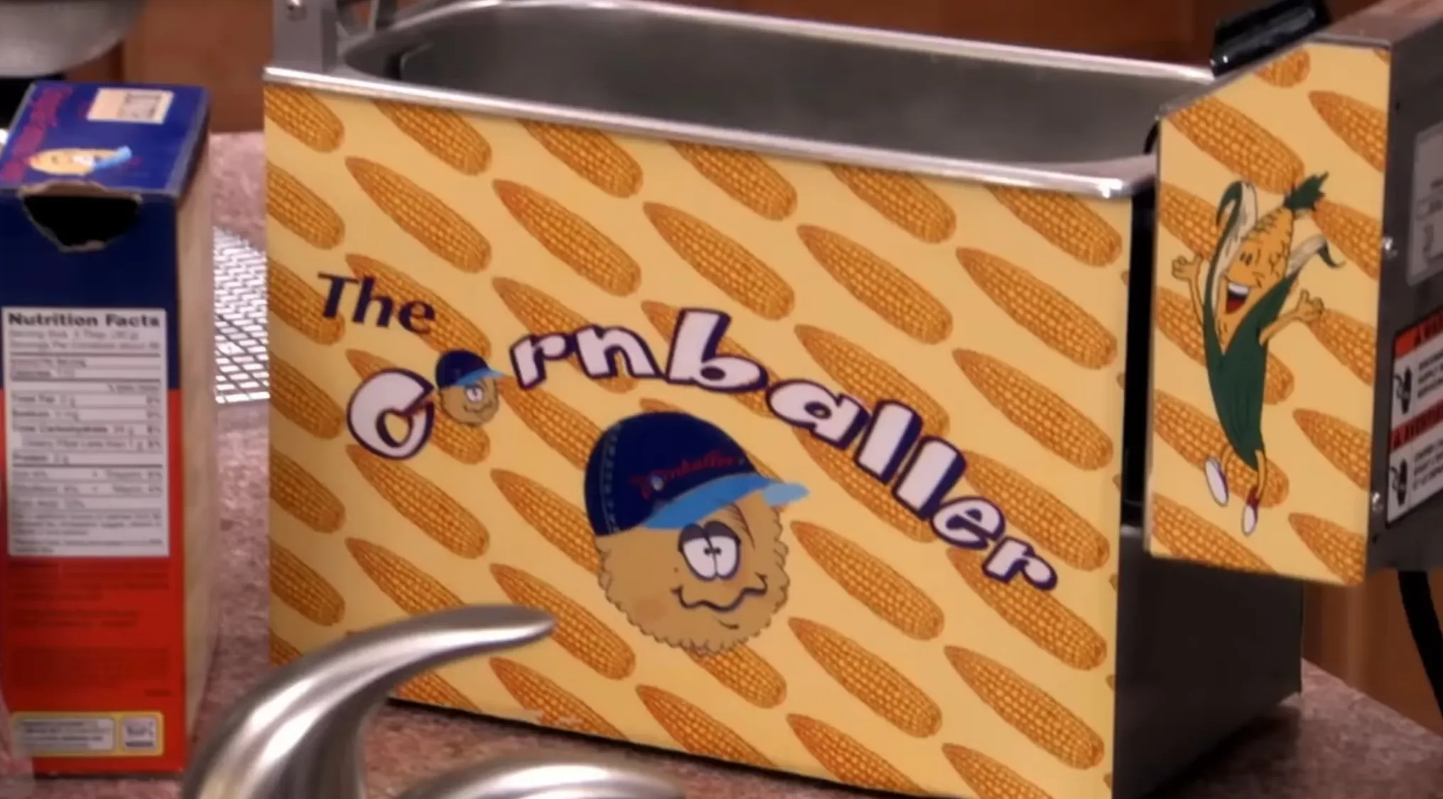 Close-up of a hazardous kitchen appliance prop decorated with cartoon corn cob designs from a TV show quiz.