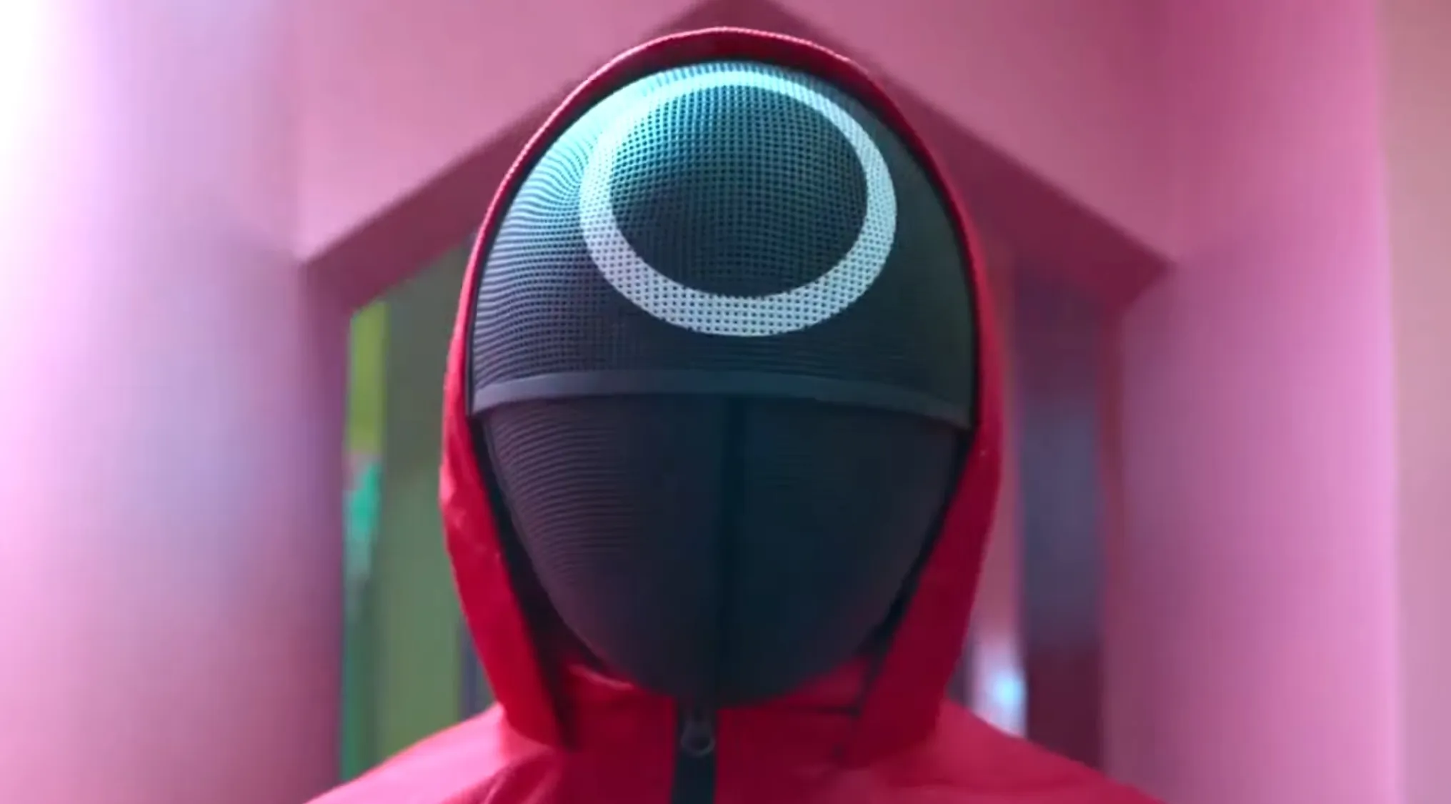 Red hooded figure wearing a black mesh mask with a white circle, iconic TV show props quiz image from a popular series.