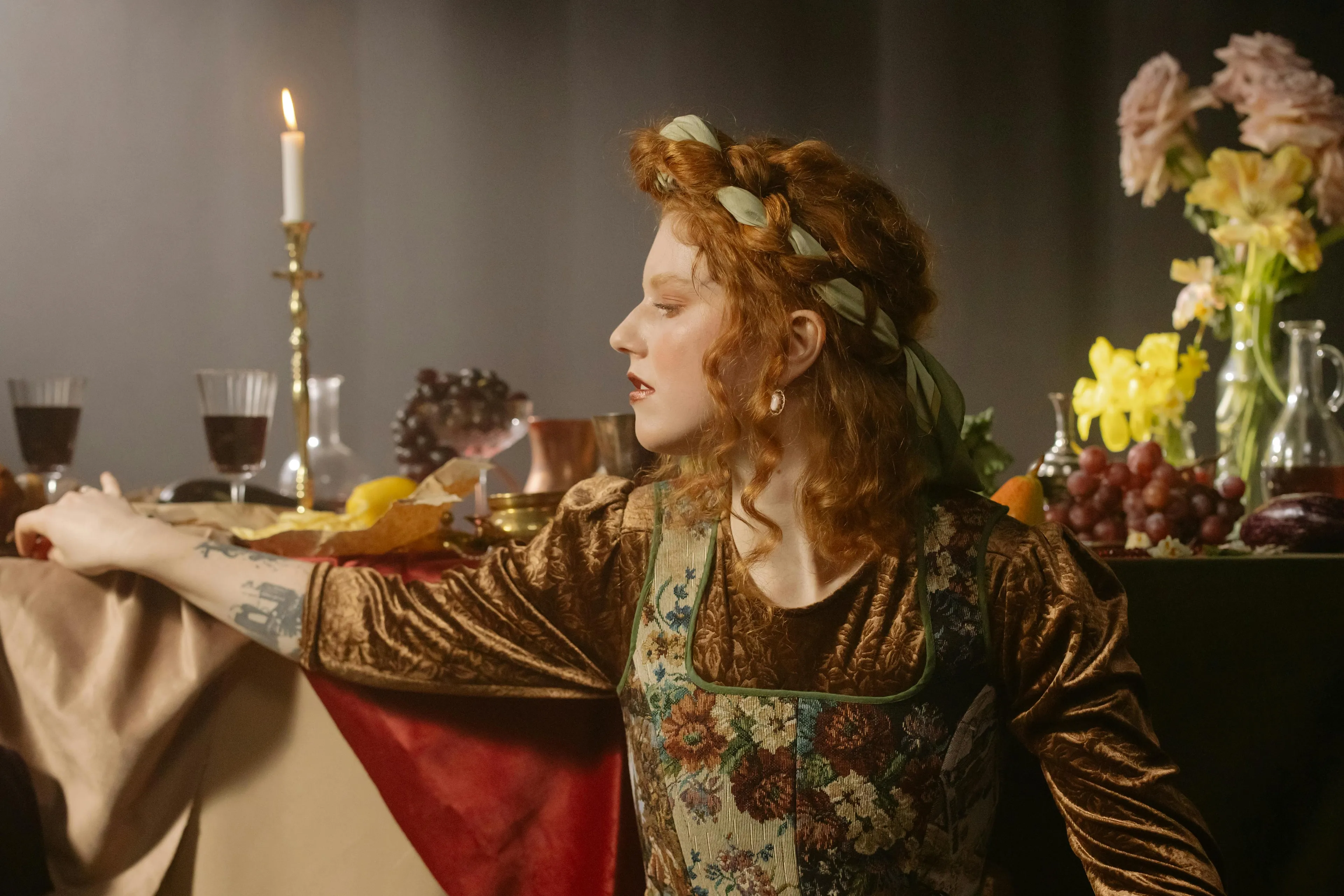 Woman in Renaissance attire at candlelit table, evoking Lady Macbeth’s soliloquies in Shakespeare’s Macbeth literature quiz.