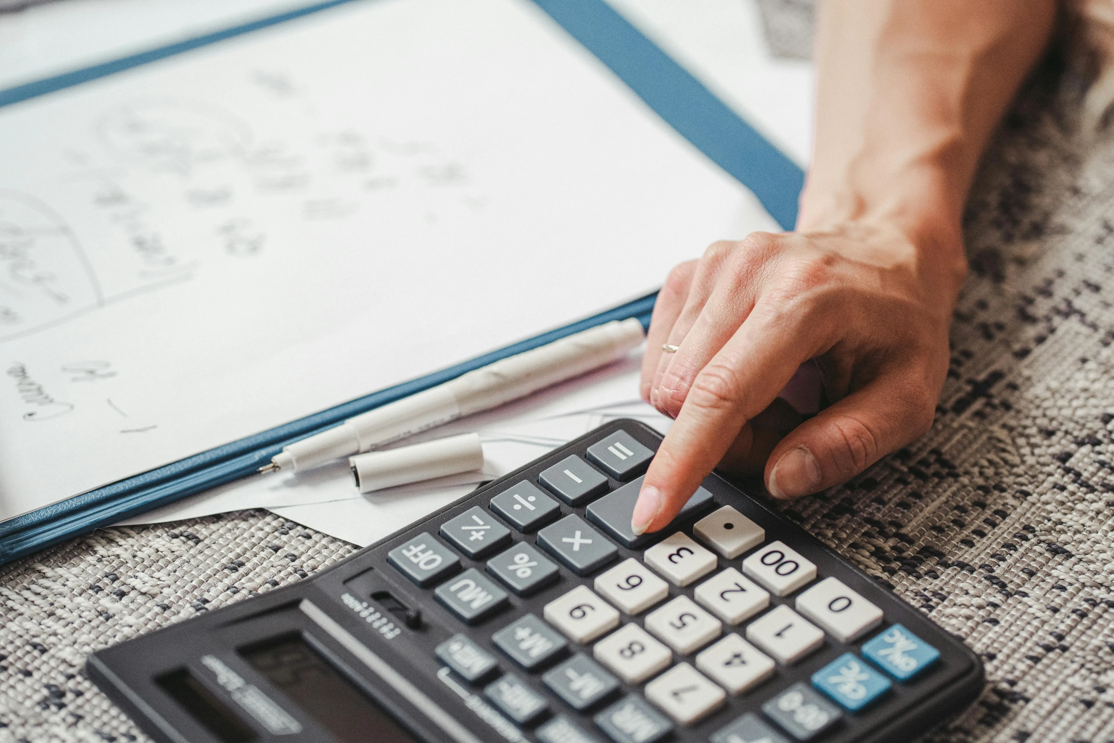 Person using calculator and writing notes on a statistics quiz involving mean and standard deviation calculations