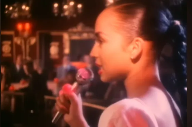 Female singer performing Smooth Operator by Sade in dimly lit lounge, ideal music choice for a dinner party ambiance.