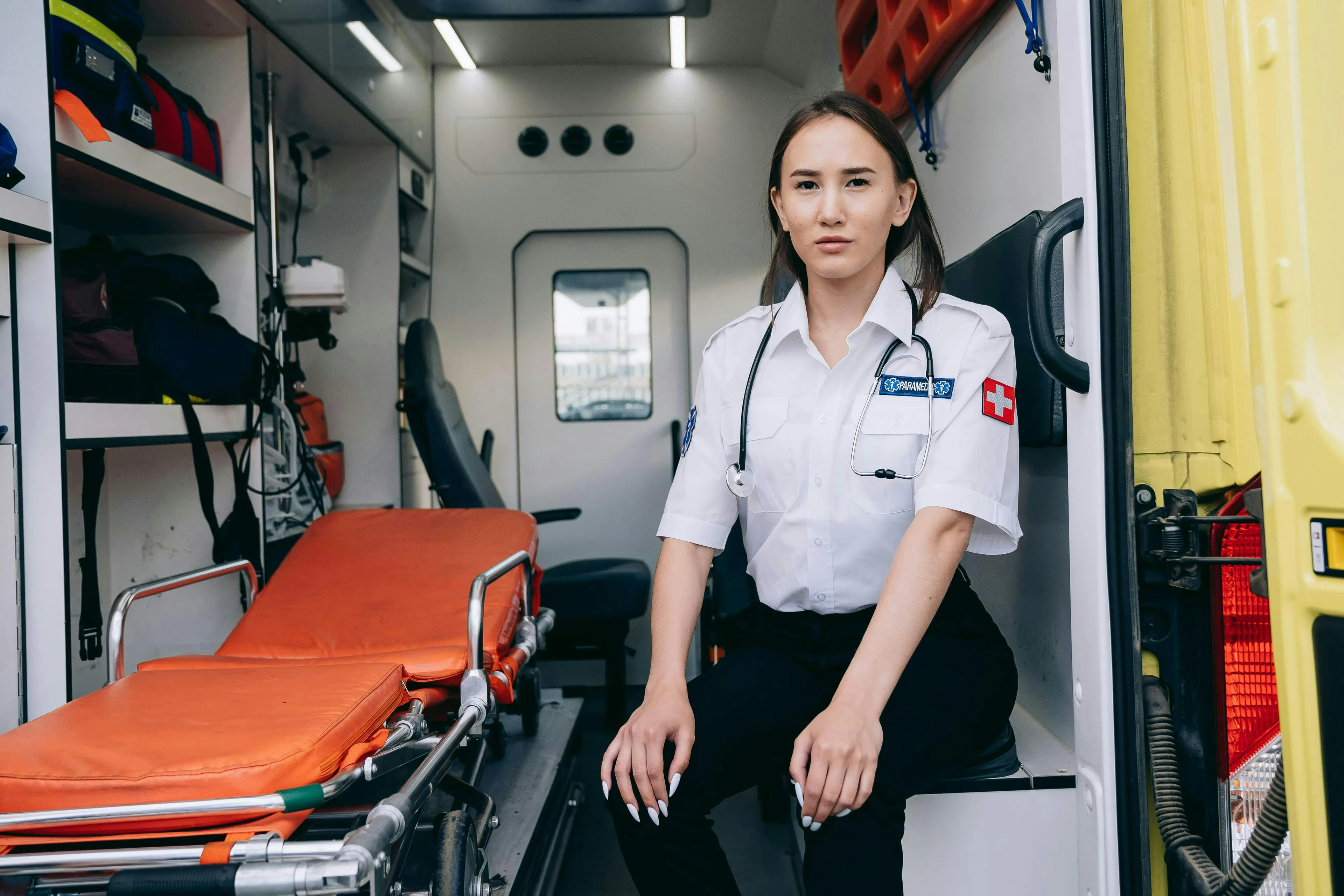 Paramedic sitting inside an ambulance next to medical equipment, highlighting emergency aid programs and charity support.