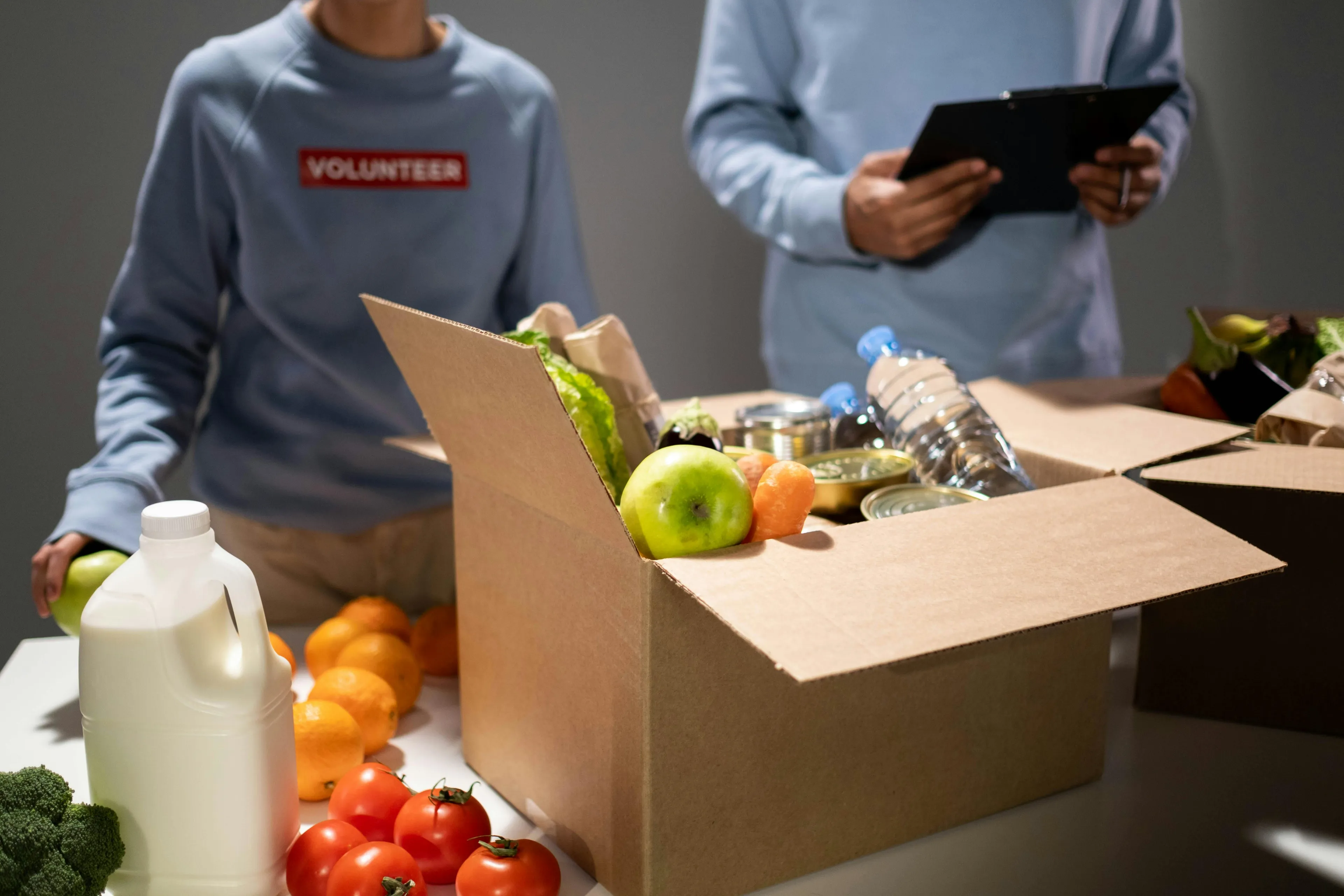 Volunteers packing food donations including fruits and water bottles at a local food bank for charity distribution.