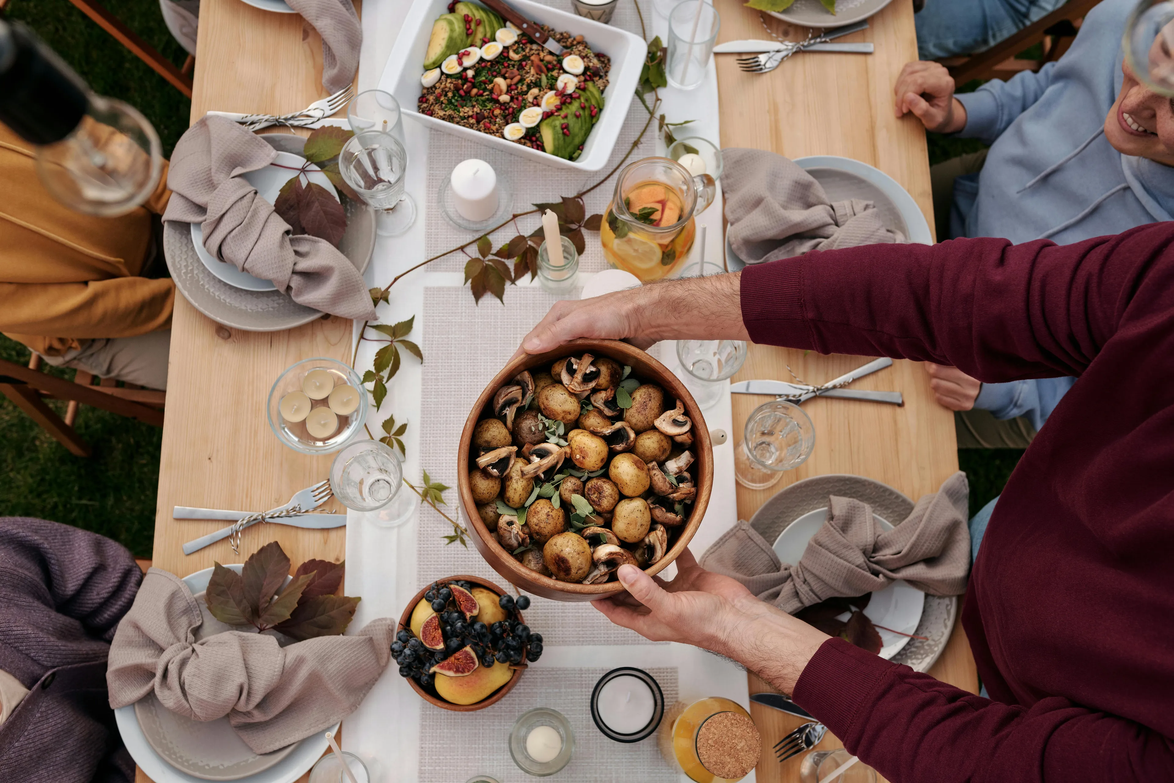 People sharing a meal at a wooden table with various dishes, illustrating decision making style and recipe selection.