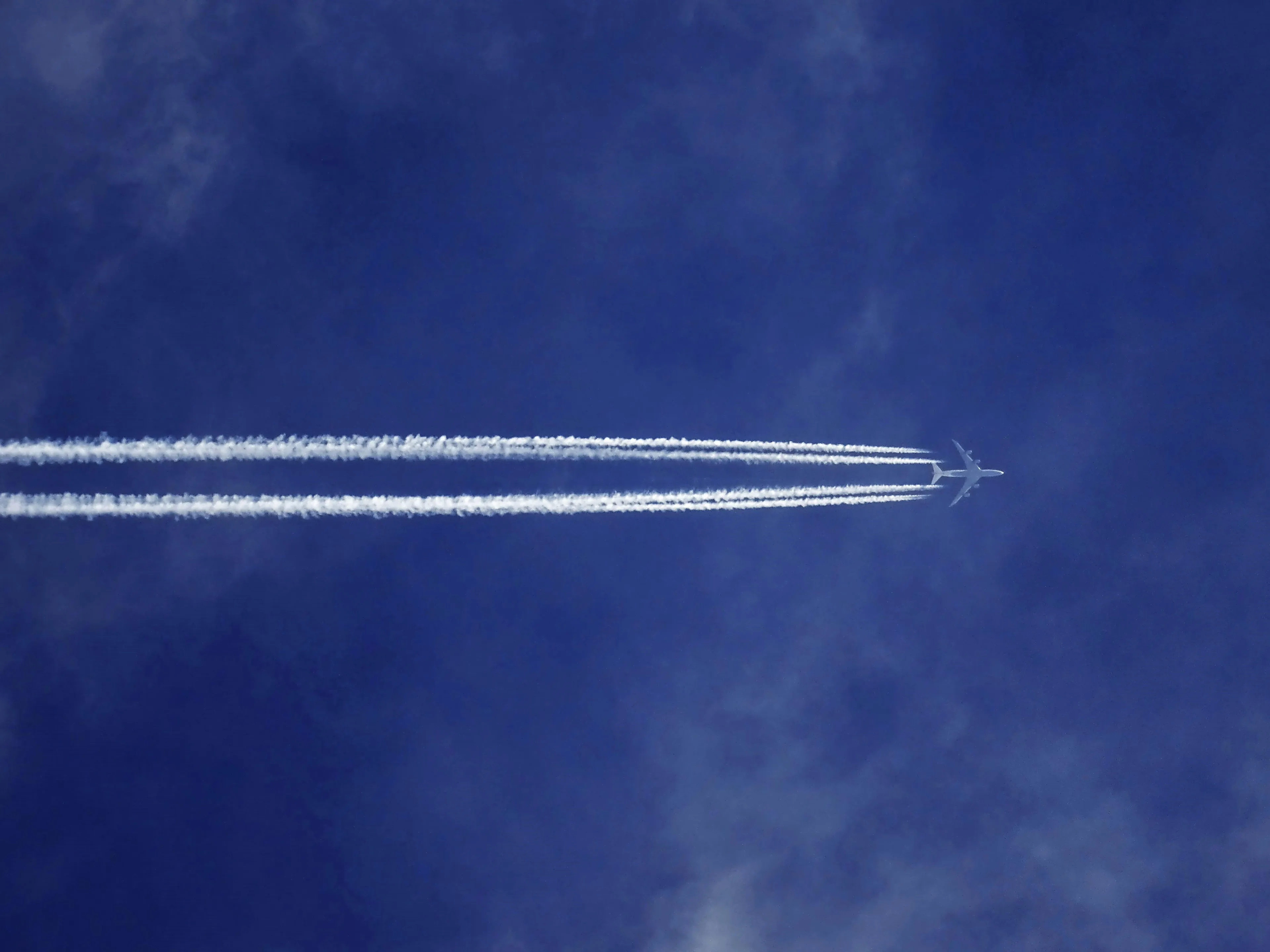 Airplane flying high in clear sky leaving contrails, illustrating booking holiday flights decision making style.