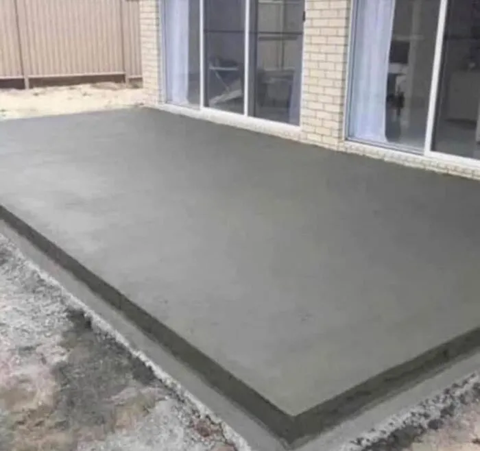 Freshly poured concrete slab near house windows, highlighting uncultured and ignorant Americans in construction choices.