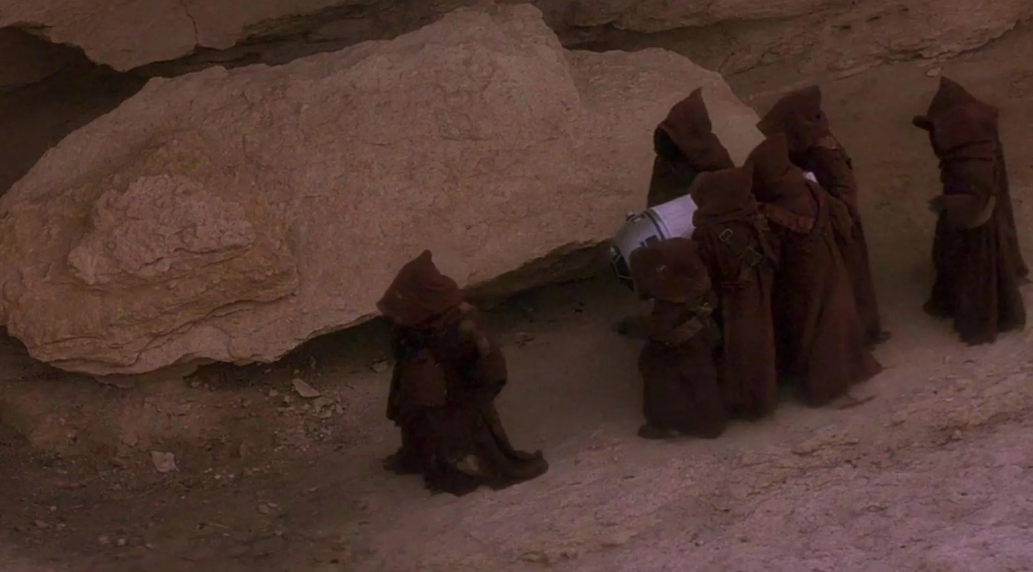 1970s movie scene with cloaked figures carrying a droid in a rocky desert setting from classic 70s movie scenes