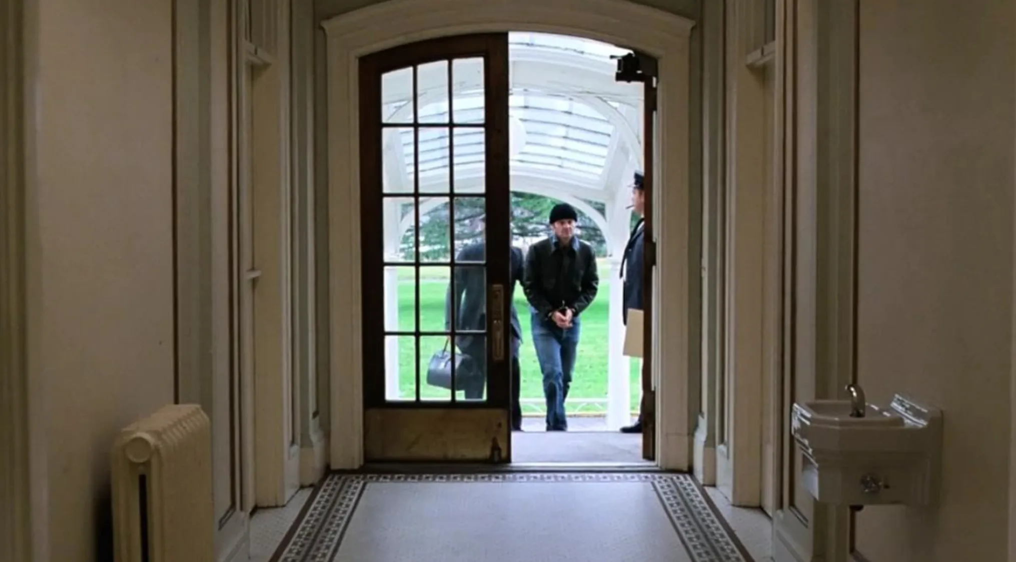 View through hallway door showing men outside in vintage setting from 70s movie scenes to uncover.