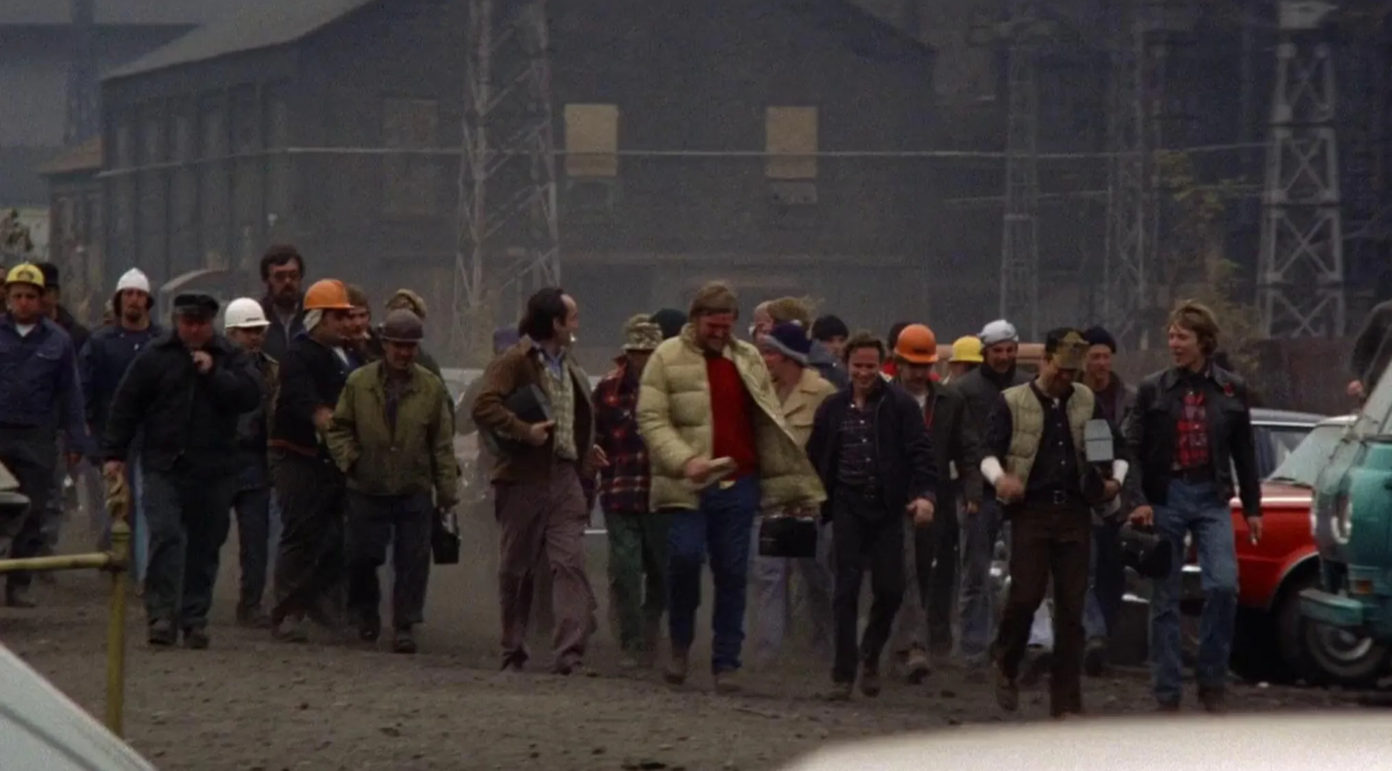 Group of workers walking together in an industrial area in a 70s movie scene with vintage clothing and helmets