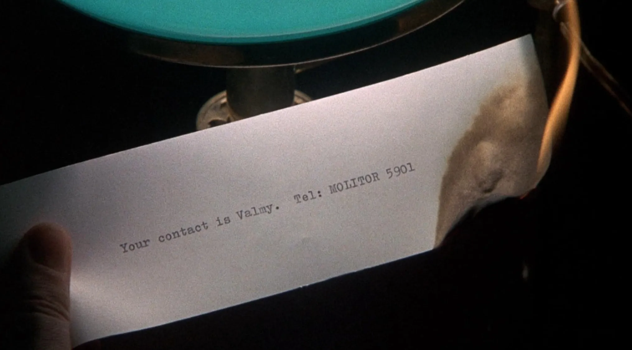 Close-up of a burning note revealing a contact in a 70s movie scene for you to uncover.