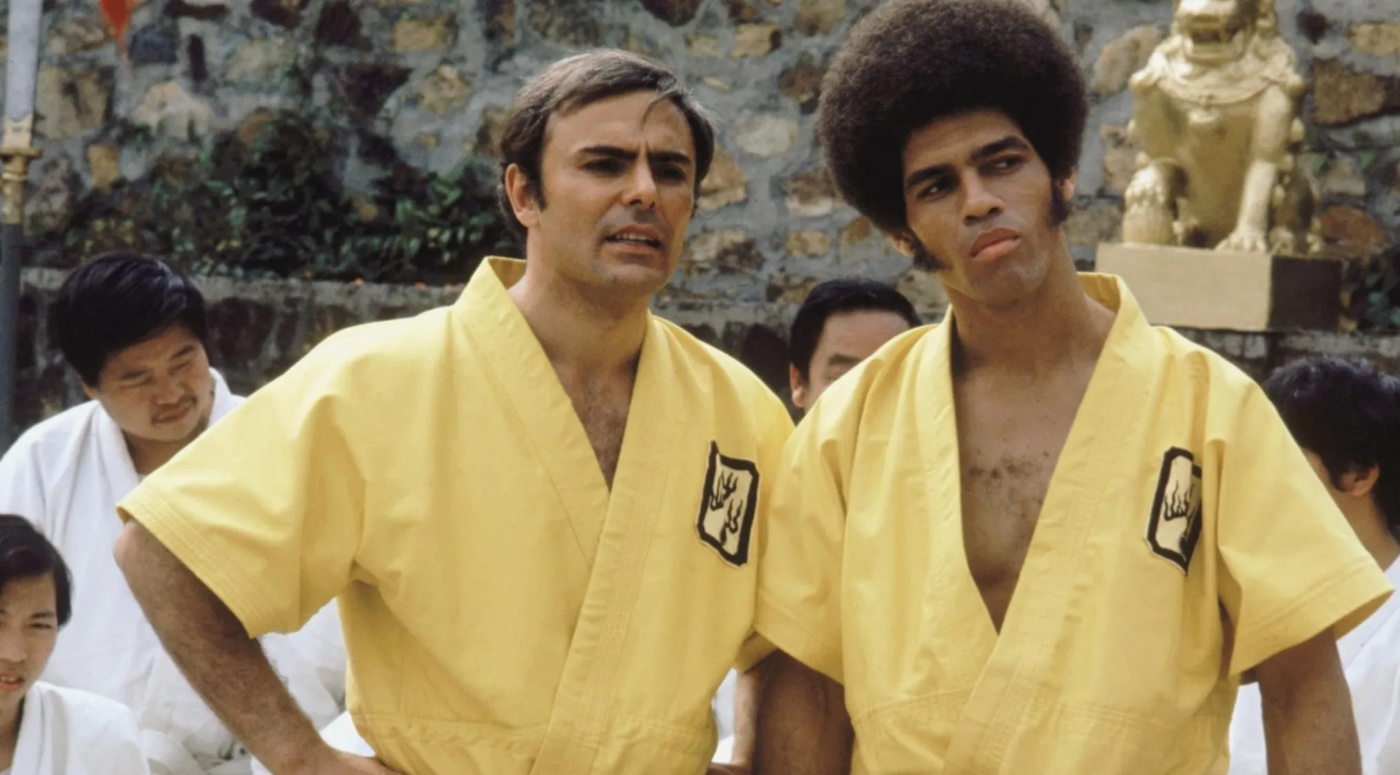 Two men in yellow karate uniforms in a 70s movie scene, part of iconic 70s movie scenes to uncover which movie