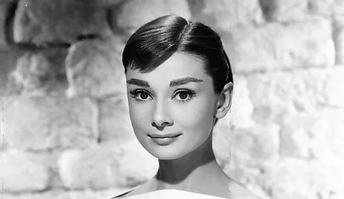 Audrey Hepburn in a classic black and white portrait, exemplifying her iconic style from Roman Holiday (1953).