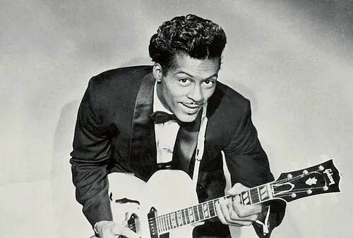 Chuck Berry playing guitar wearing a tuxedo, known as a pioneer in rock and roll music.
