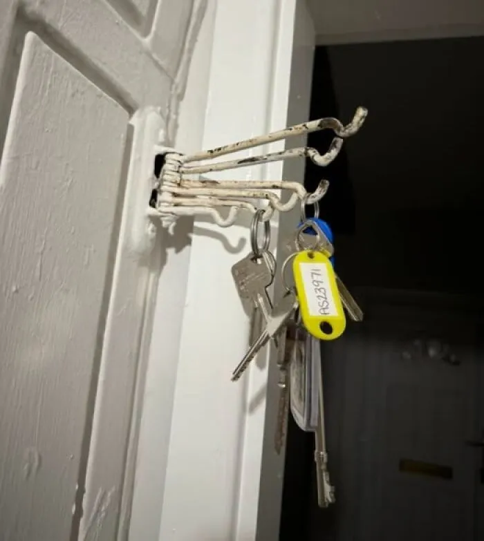 Rusty wall-mounted hooks holding a set of keys with tags, an example of internet solving mystery of unidentified objects.