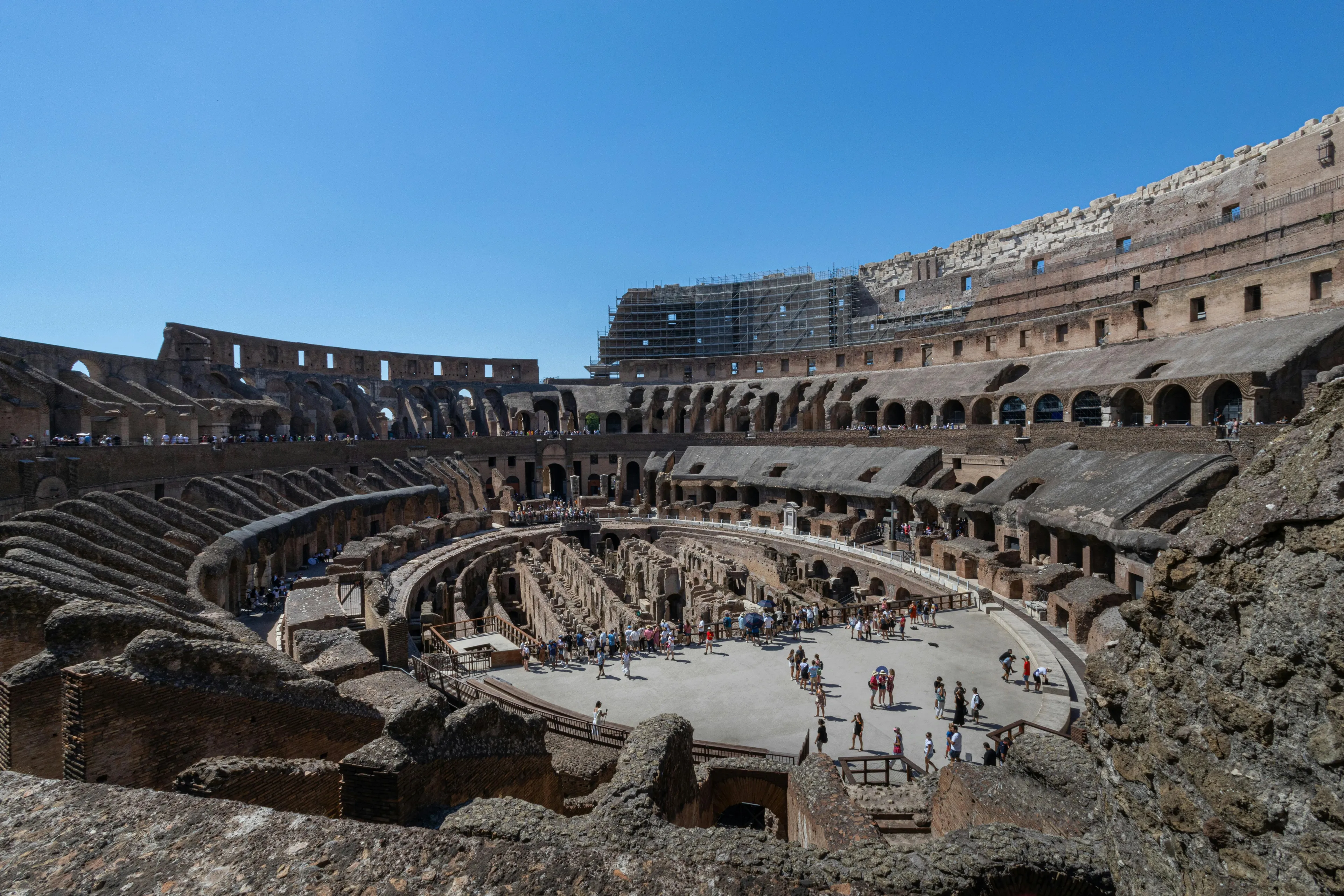 The Colosseum in Rome, filled with tourists exploring the ancient amphitheater on a clear sunny day.