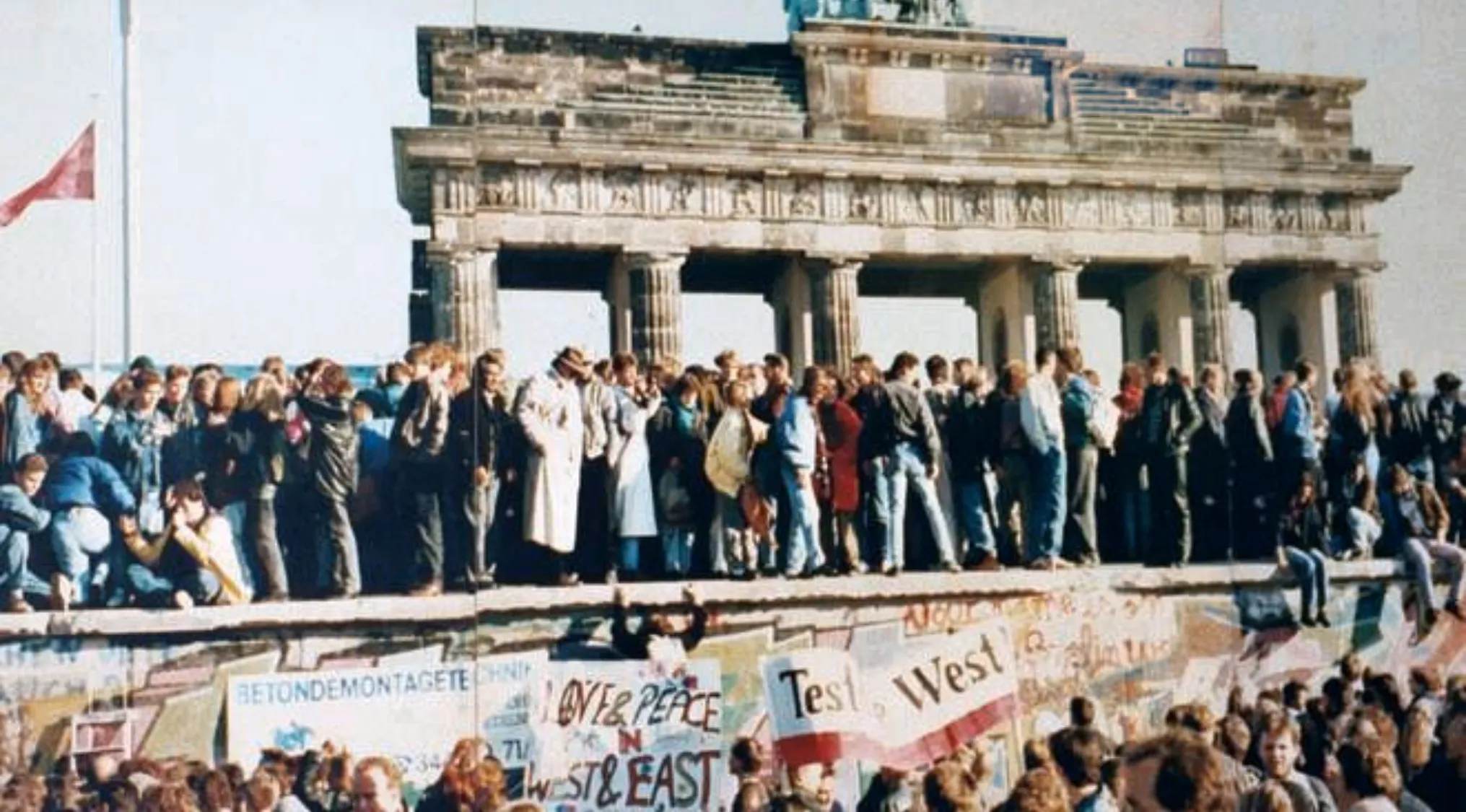 Crowd gathered on the Berlin Wall during its fall in 1989, a key moment in history quiz about the Berlin Wall.