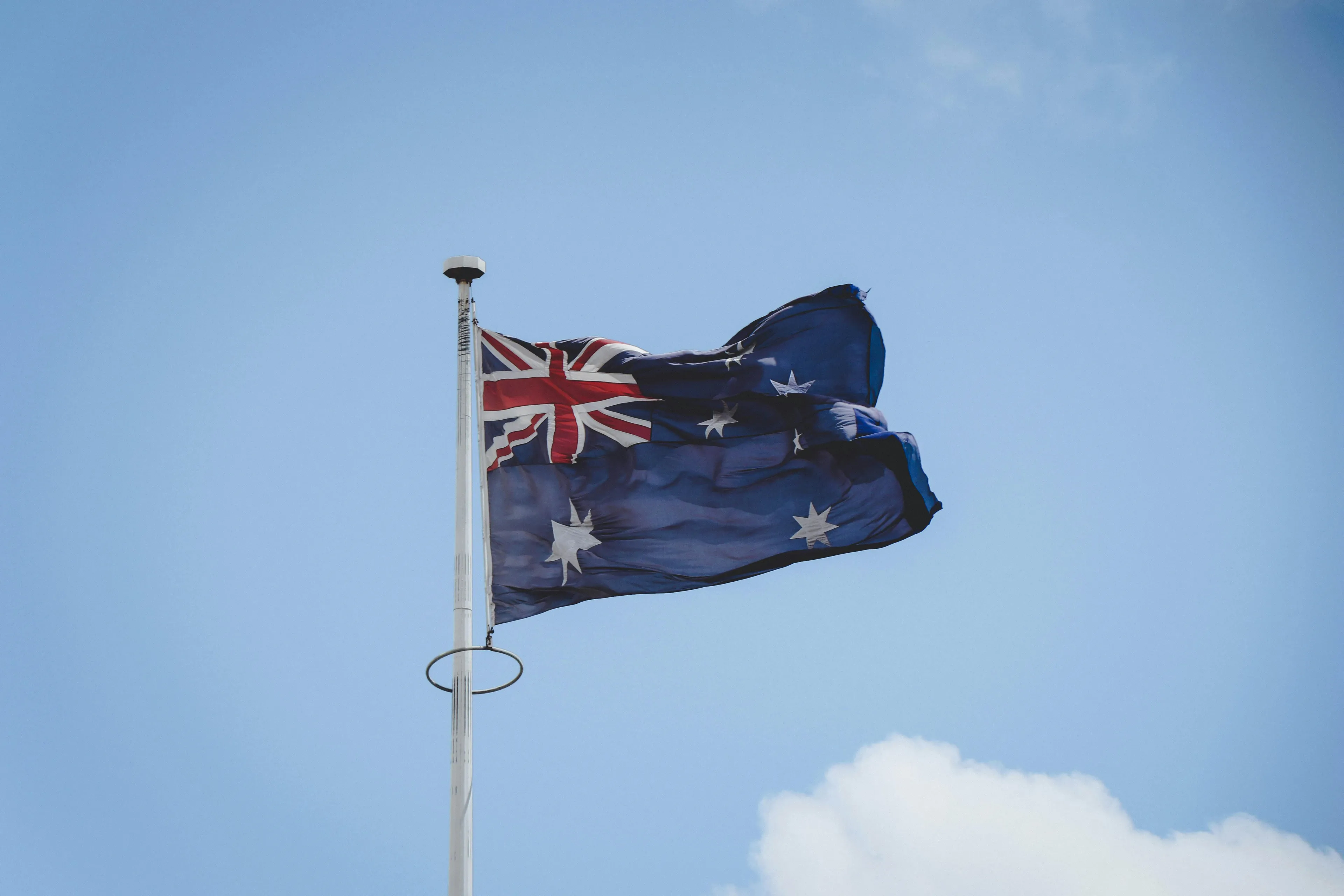 Australian flag waving on a flagpole under clear sky, related to capital city of Australia quiz topic.