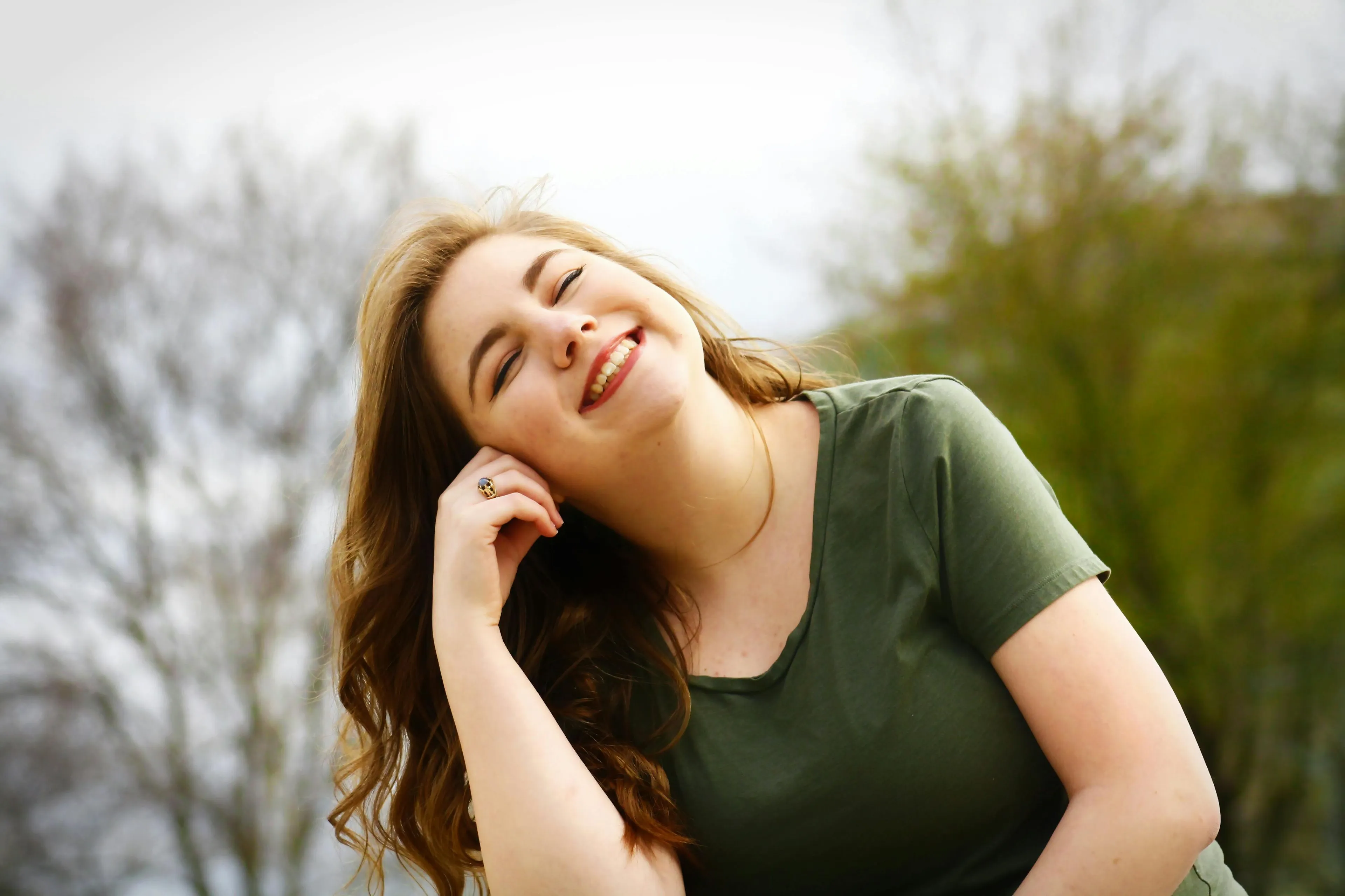 Young woman smiling outdoors in a green shirt, representing the largest internal organ in the human body quiz concept.