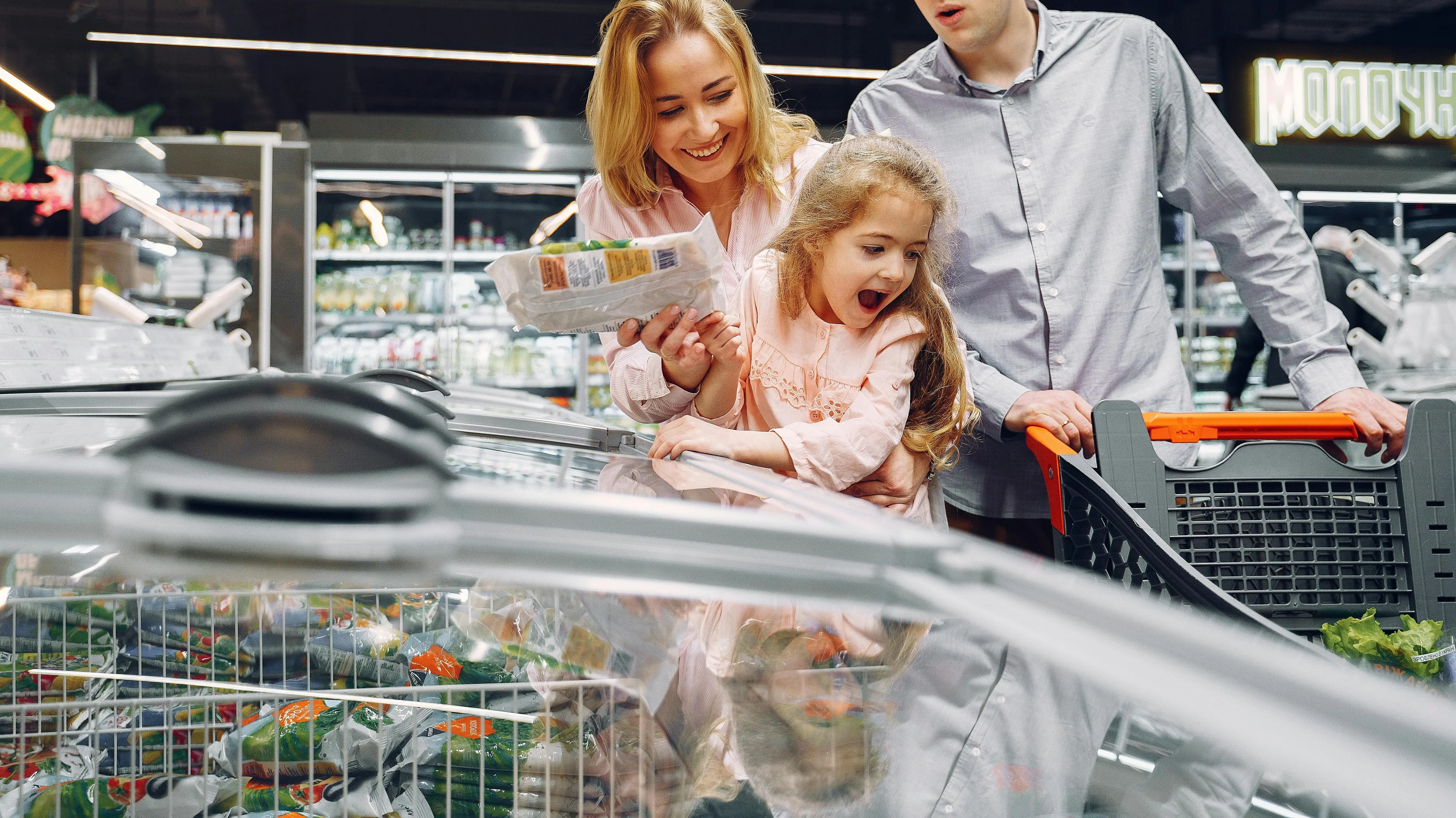 Family shopping frozen food in a supermarket freezer section, exploring food products that may still have live bacteria.