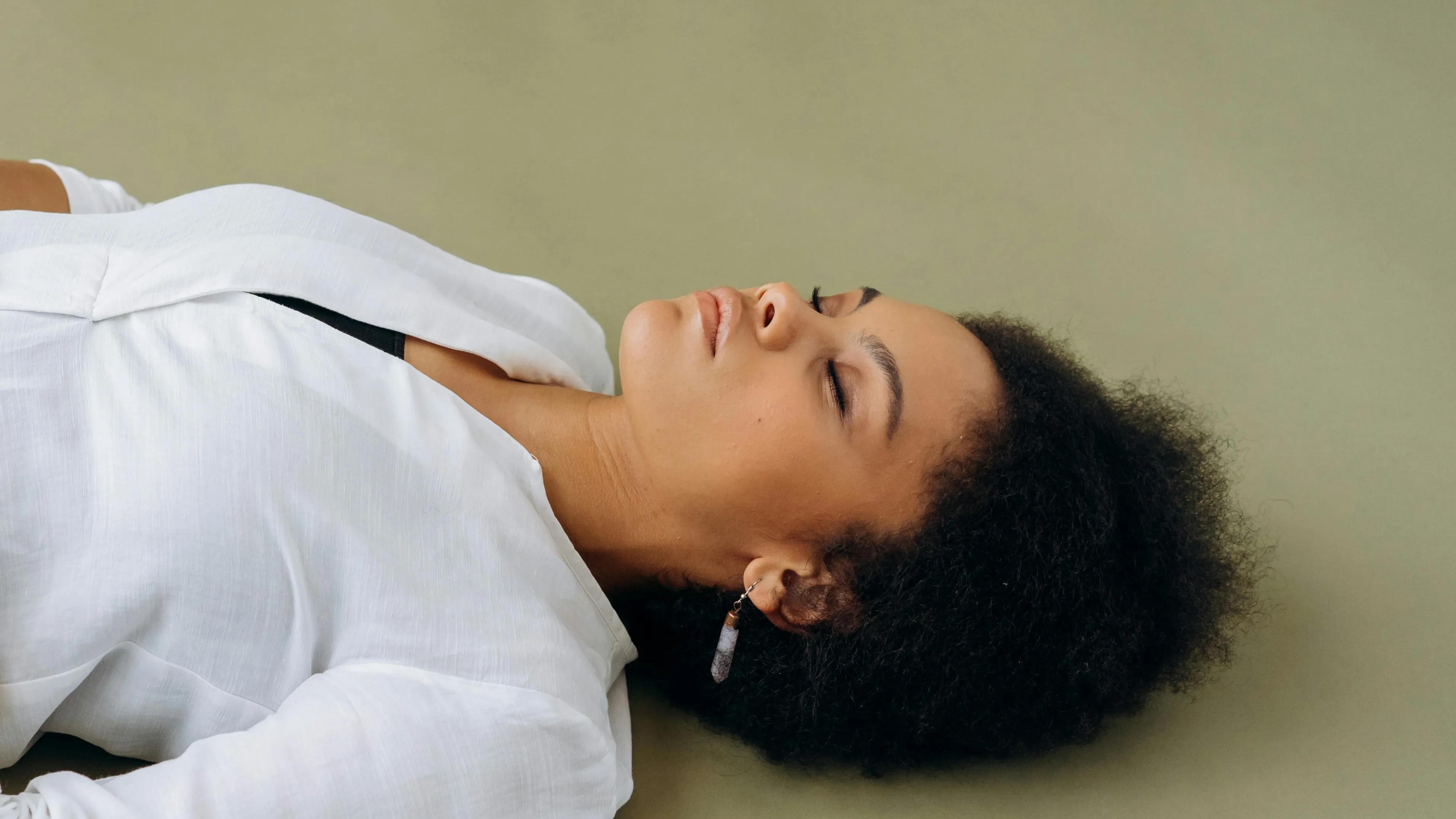 Young woman lying unconscious on the floor with eyes closed, illustrating safest sequence of steps to help an unconscious person