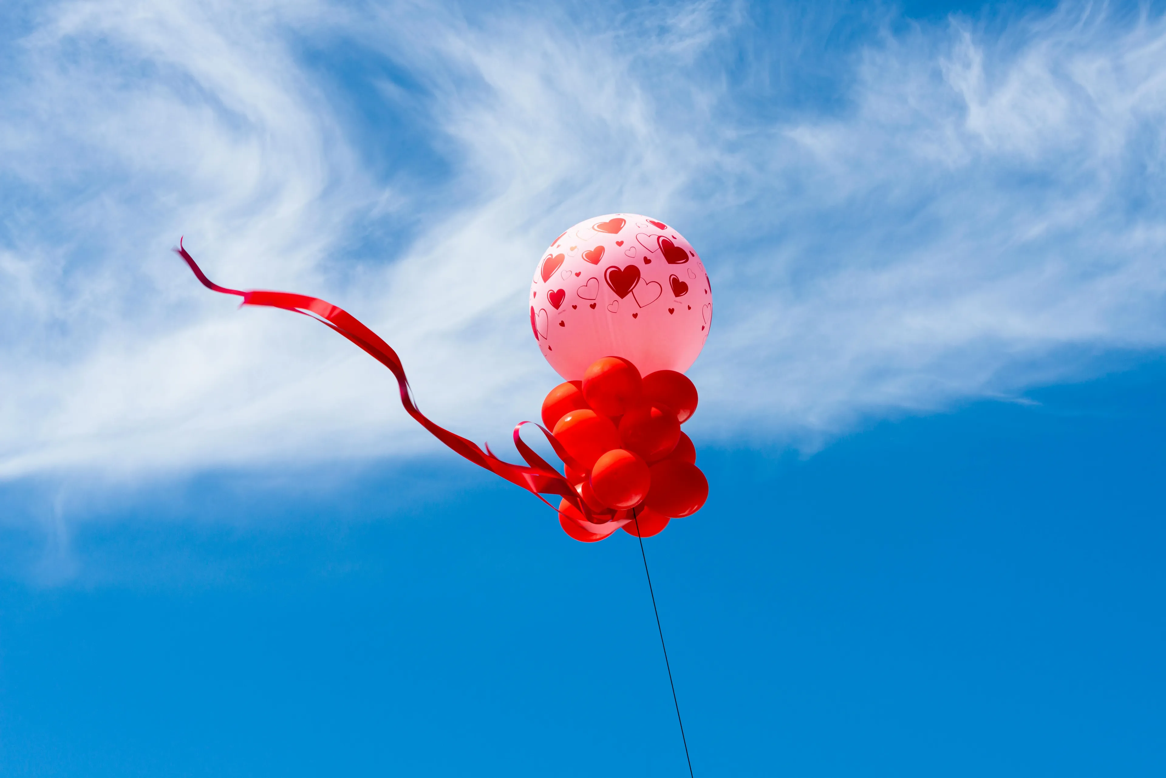 Helium-filled balloon with heart patterns floating against blue sky, illustrating general science knowledge quiz concept.
